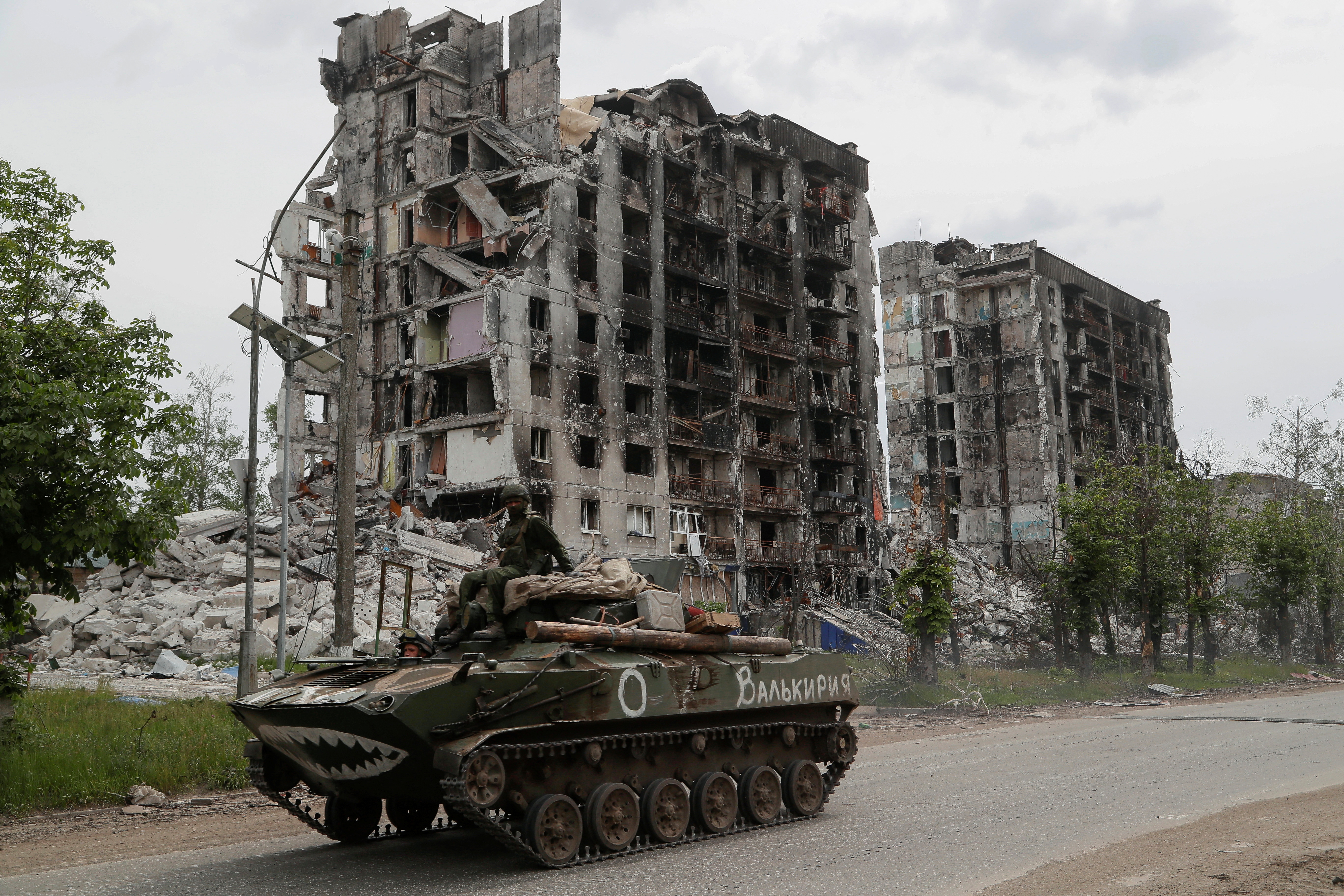 Service members of pro-Russian troops drive an armored vehicle along a street past a destroyed residential building during Ukraine-Russia conflict in the town of Popasna in the Luhansk Region, Ukraine, Thursday. The writing on the vehicle reads: "Valkyrie."