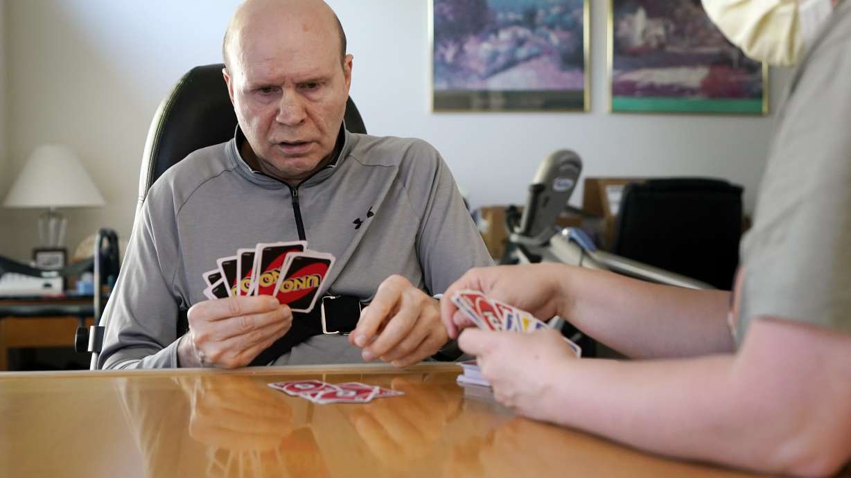 Former Detroit Red Wings star Vladimir Konstantinov plays Uno with health care provider Angela Martin, Tuesday, May 17, 2022, in West Bloomfield, Mich. Konstantinov is in danger of losing the 24/7 care he has had for two-plus decades. The disabled former NHL defenseman is a casualty of changes to Michigan's auto insurance law that curbed or cut what hospitals, residential care facilities and home providers can charge car insurers for care. Konstantinov suffered a severe brain stem injury from an accident in a limousine with an impaired driver after a Stanley Cup celebration nearly 25 years ago.