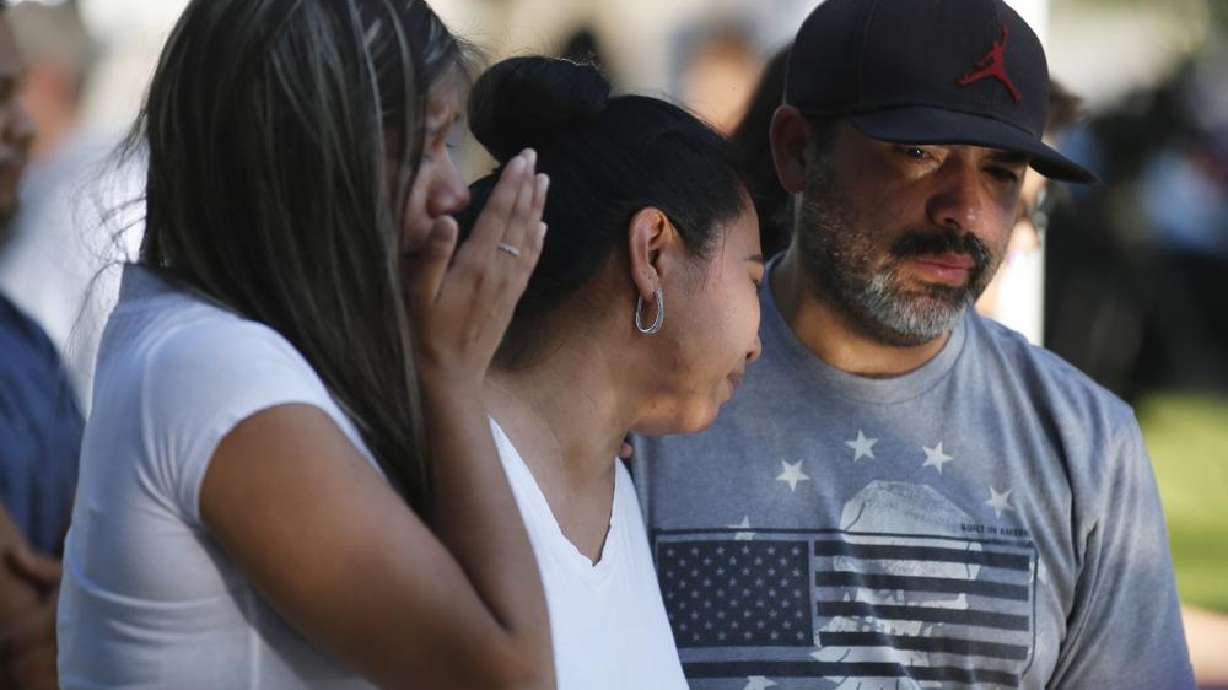 Mario Games, right, and his wife, Marisela and daughter Emily, stand in front of a cross with the name of their niece, Nevaeh Bravo, at a memorial site for the victims killed in this week's elementary school shooting in Uvalde, Texas, Thursday. Students trapped inside a classroom with a gunman repeatedly called 911 during this week's attack at the school.
