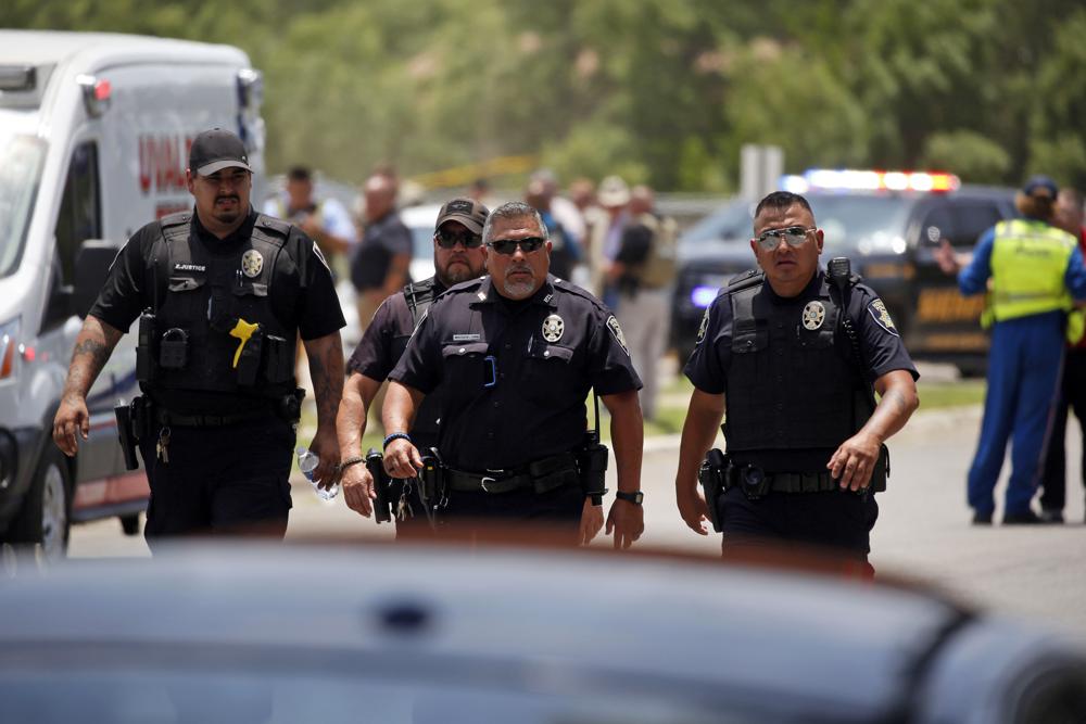 Police walk near Robb Elementary School following a shooting, Tuesday, in Uvalde, Texas.