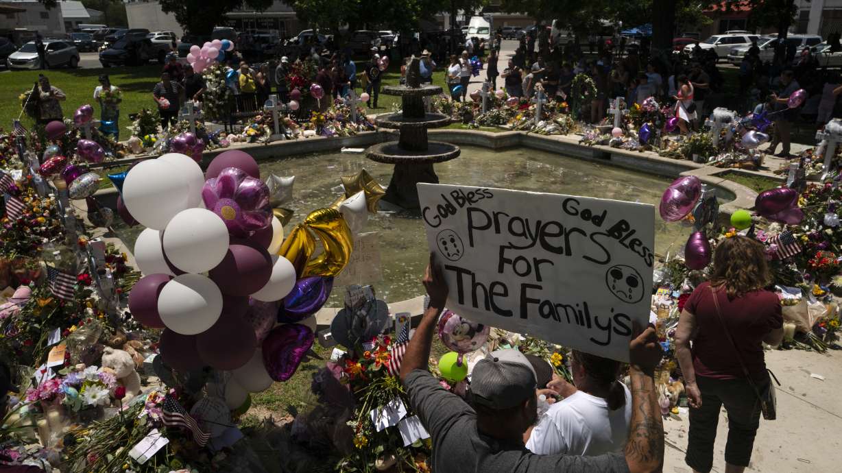 People visit a memorial set up in a town square to honor the victims killed in this week's elementary school shooting in Uvalde, Texas, Saturday. Days after a local man burst into an elementary school and killed 19 children and two teachers before officers managed to kill him, the signs of grief, solidarity and local pride are everywhere in Uvalde, Texas.
