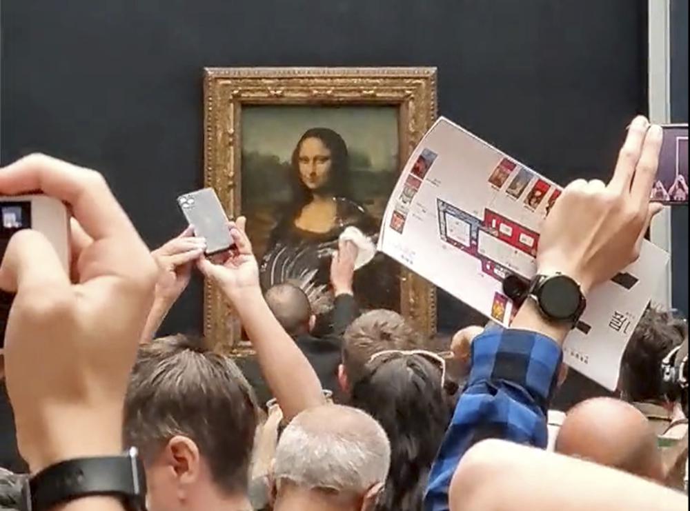 Man in wig throws cake at glass protecting Mona Lisa