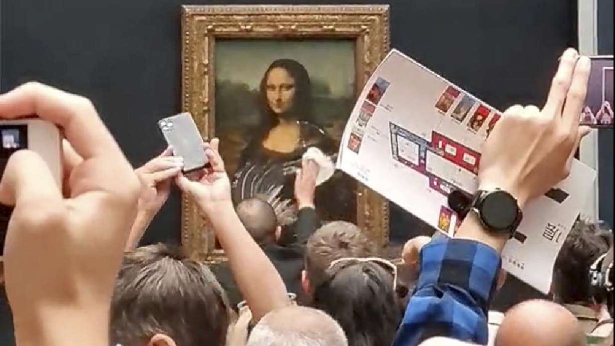 A security guard cleans cake off the glass protecting the Mona Lisa at the Louvre Museum, in Paris, France, Sunday. A man seemingly disguised as an old woman in a wheelchair threw a piece of cake at the glass protecting the Mona Lisa and shouted at people to think of planet Earth.