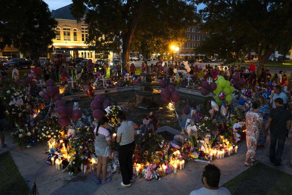 People visit a memorial set up in a town square to honor the victims killed in the elementary school shooting earlier in the week in Uvalde, Texas, late Saturday.