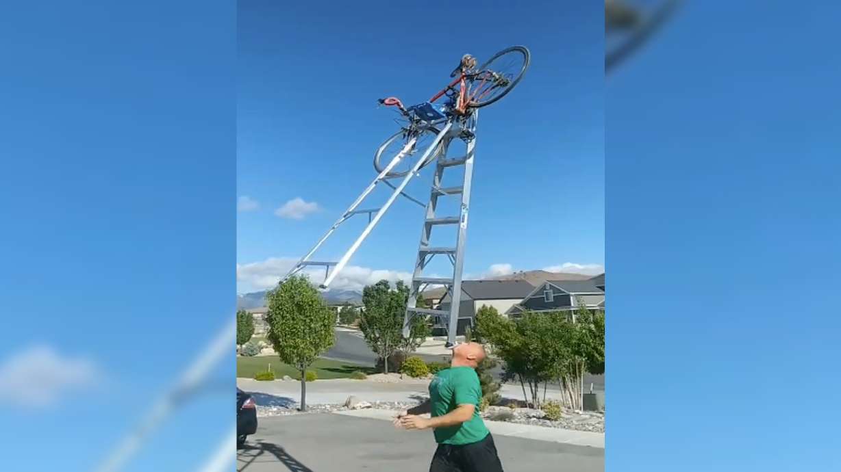 Former BYU defensive tackle and Salt Lake City radio host Hans Olsen balances a bike on top of his ladder on his chin after a bet with his son Tommy.