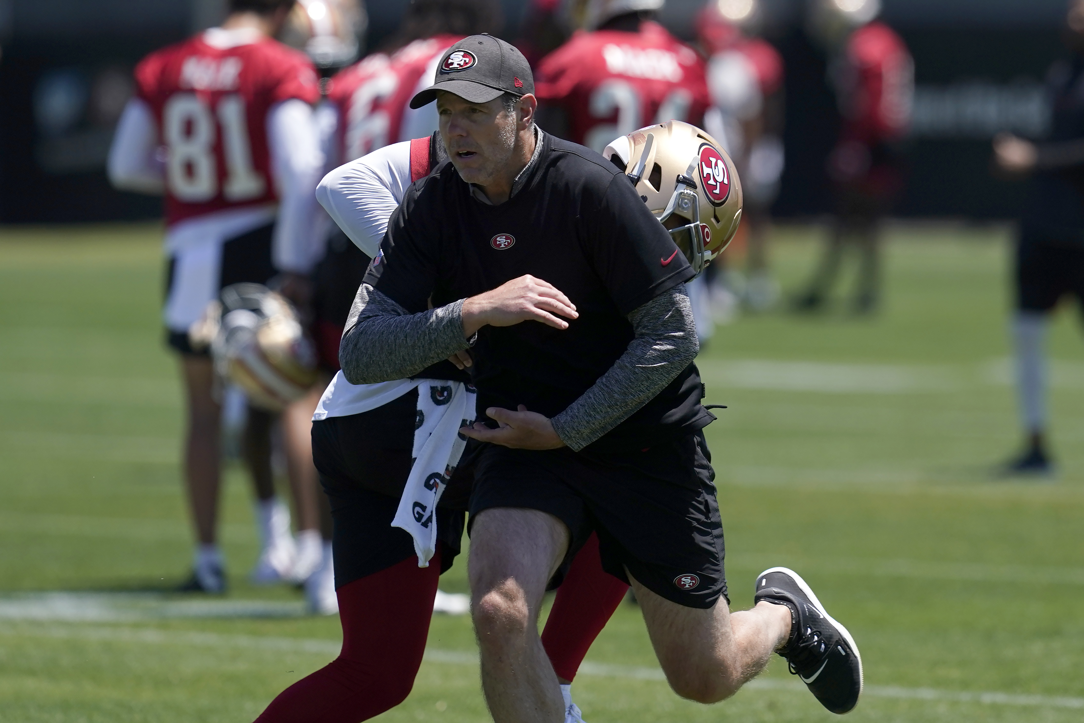 San Francisco 49ers quarterbacks coach Brian Griese, foreground, runs a drill with quarterback Trey Lance at the NFL football team's practice facility in Santa Clara, Calif., Tuesday, May 24, 2022. Griese, an 11-year quarterback in the NFL, left the cushy work of a broadcaster to get back into the grind of the NFL as the 49ers quarterbacks coach tasked with developing Lance into a star. 