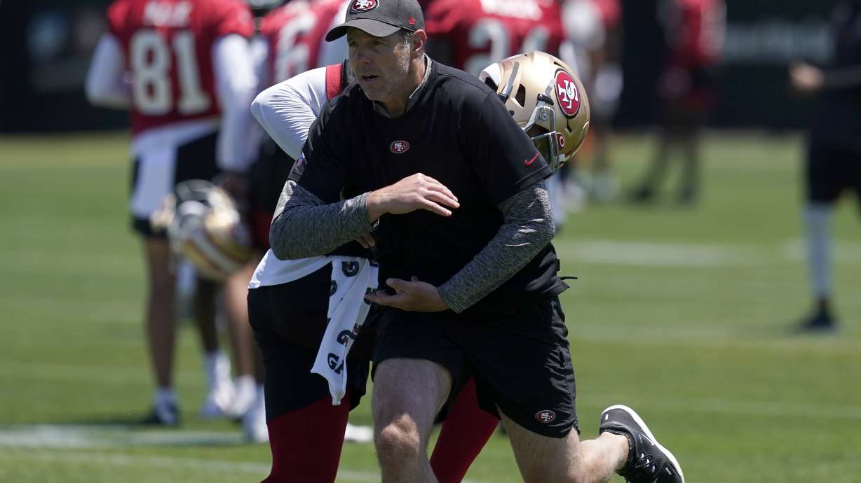 San Francisco 49ers quarterbacks coach Brian Griese, foreground, runs a drill with quarterback Trey Lance at the NFL football team's practice facility in Santa Clara, Calif., Tuesday, May 24, 2022. Griese, an 11-year quarterback in the NFL, left the cushy work of a broadcaster to get back into the grind of the NFL as the 49ers quarterbacks coach tasked with developing Lance into a star.
