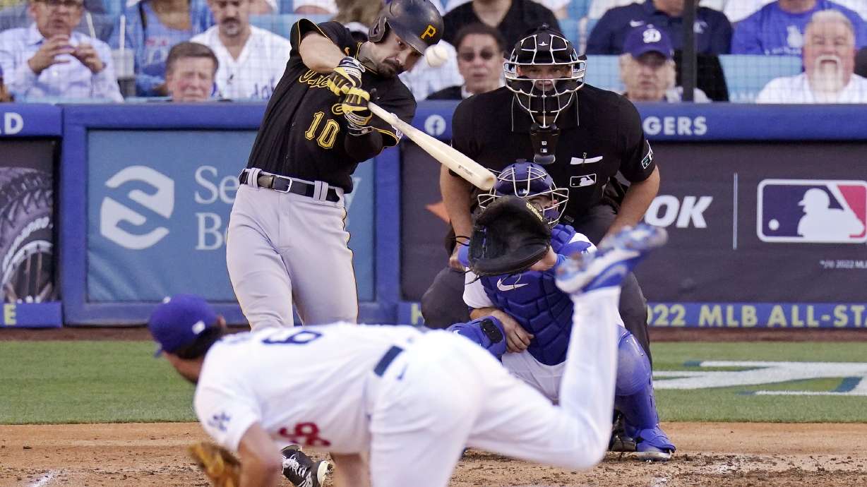 Pittsburgh Pirates' Bryan Reynolds, upper left, hits a two-run home run as Los Angeles Dodgers starting pitcher Mitch White, below, watches along with catcher Austin Barnes and home plate umpire Chad Fairchild during the fifth inning of a baseball game Wednesday, June 1, 2022, in Los Angeles.