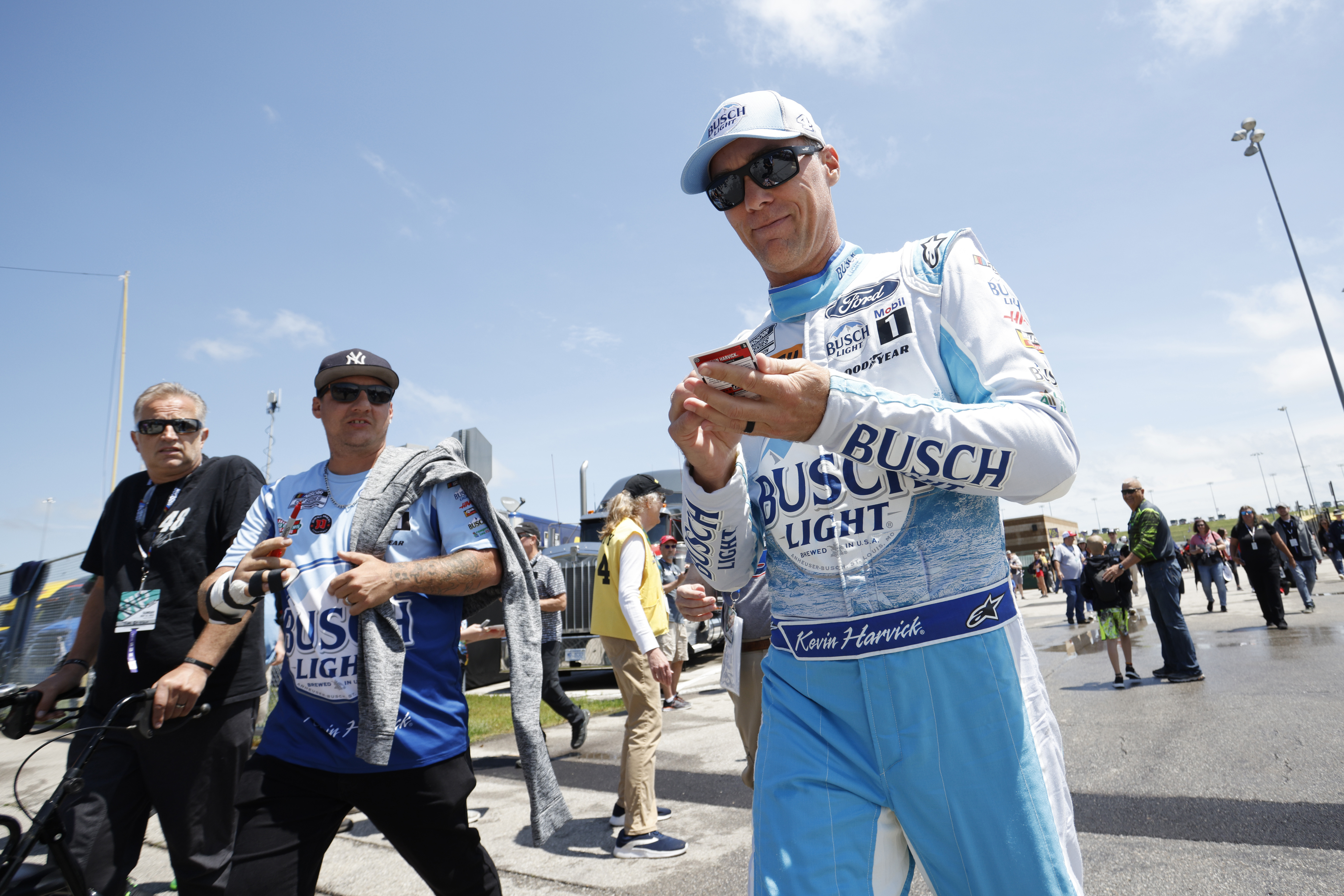 Kevin Harvick, right, signs autographs as he heads to pit road before the start of a NASCAR Cup Series auto race at Kansas Speedway in Kansas City, Kan., Sunday, May 15, 2022. 