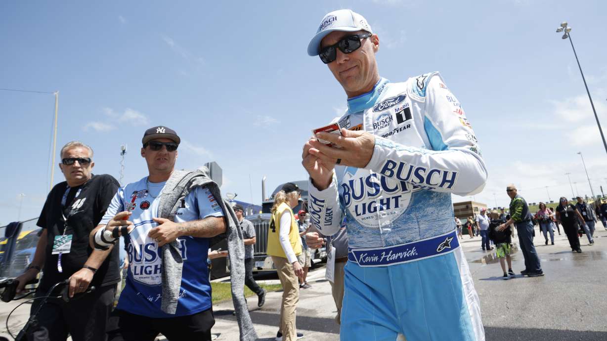 Kevin Harvick, right, signs autographs as he heads to pit road before the start of a NASCAR Cup Series auto race at Kansas Speedway in Kansas City, Kan., Sunday, May 15, 2022.