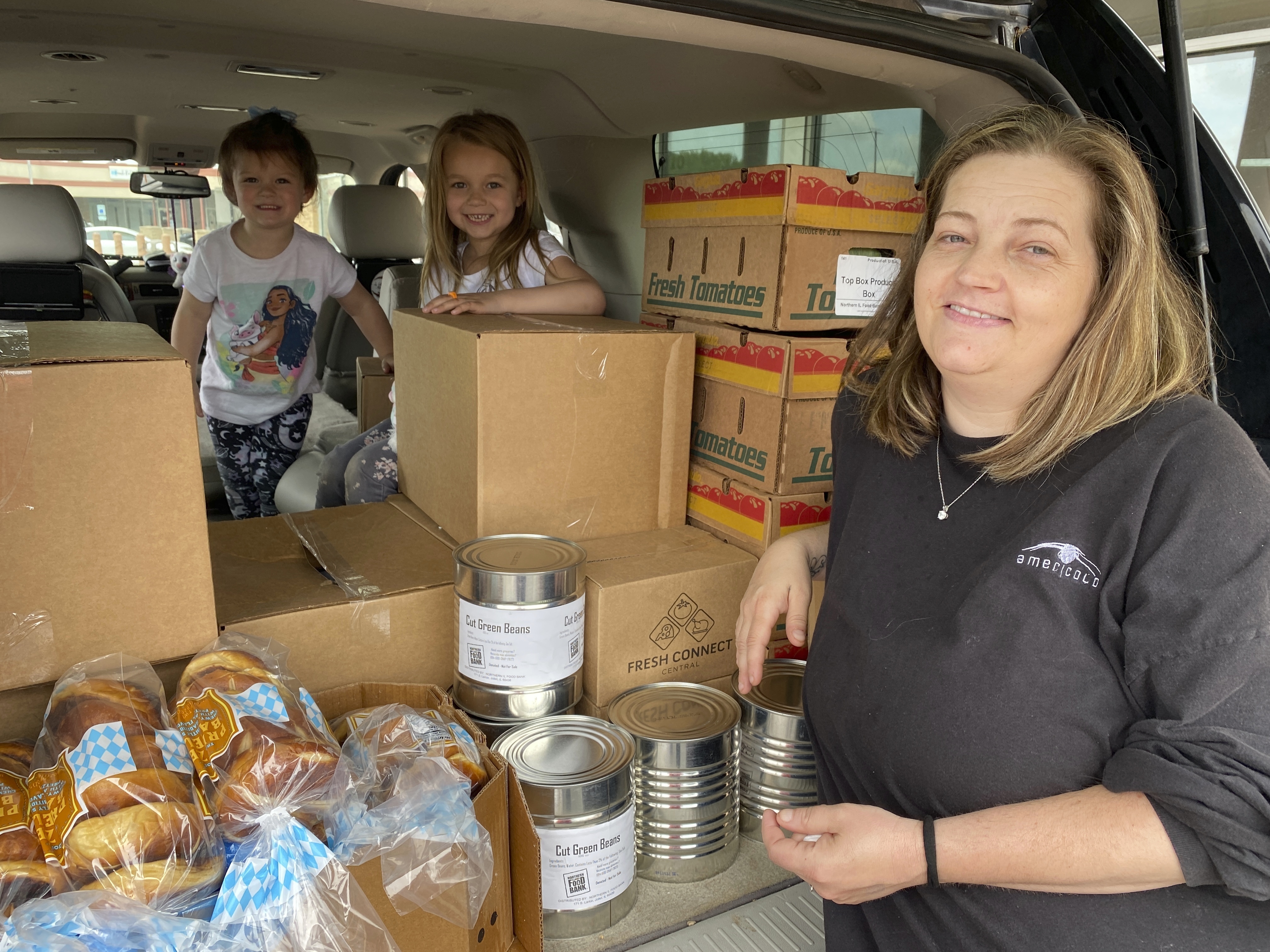In this image provided by the Northern Illinois Food Bank, Kisha Galvan and her grandchildren, pose for a photo after stocking up on food items from the Northern Illinois Food Bank on May 26, in Rockford, Ill. Galvan was able to stock up on groceries for the week and buy extras like clothing and shoes at Walmart for her children last year. 