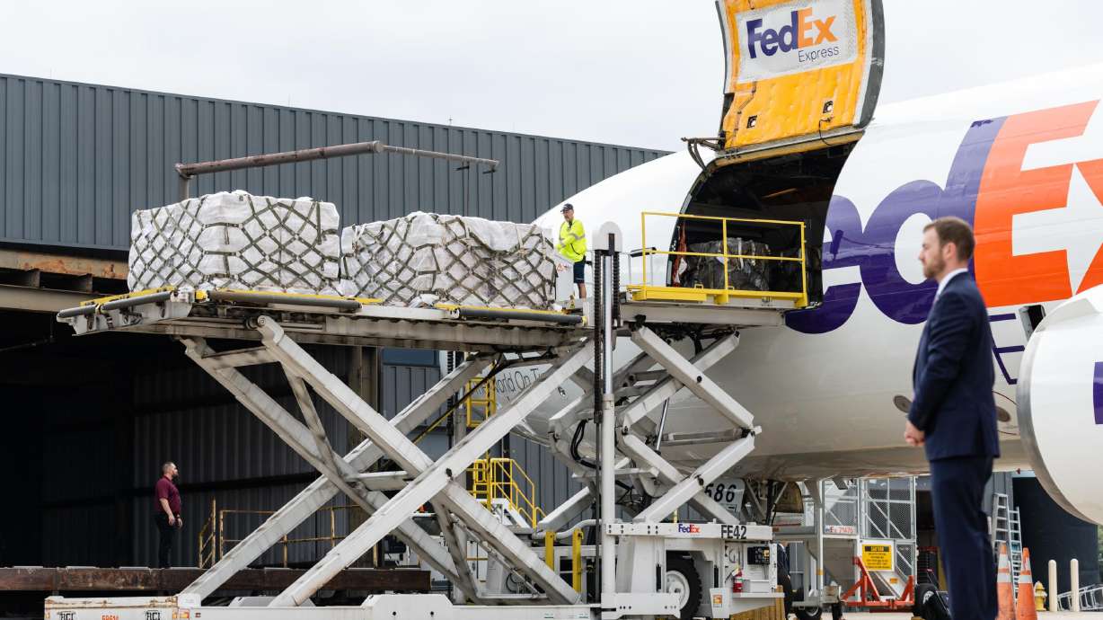 Workers unload a FedEx Express cargo plane carrying infant formula as a Secret Service agent stands watch at Dulles international airport in Dulles, Virginia, on May 25.