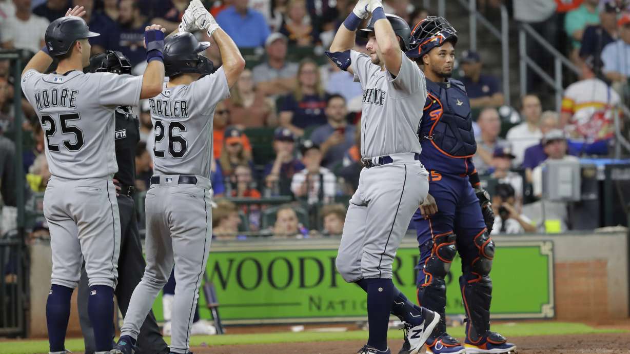 Seattle Mariners' Cal Raleigh, right, celebrates with Dylan Moore (25) and Adam Frazier (26) after they all scored on the three-run home run by Raleigh during the second inning of a baseball game against the Houston Astros, Monday, June 6, 2022, in Houston.
