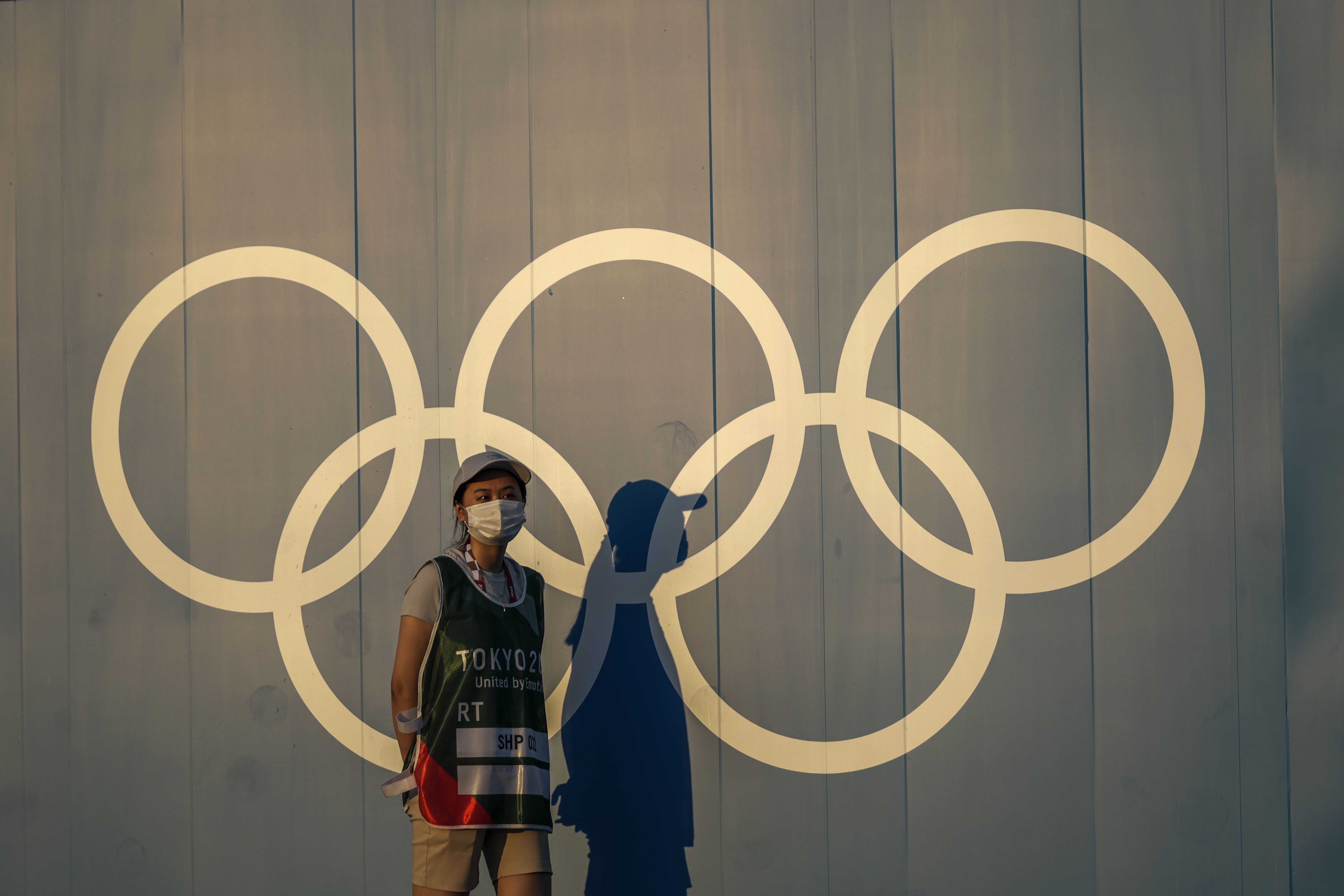 A volunteer walks past the Olympic rings ahead of the 2020 Summer Olympics in Tokyo on July 22, 2021. Japan’s northern city of Sapporo on Monday rejected holding a referendum to give voters a choice over bidding for the 2030 Winter Olympics.