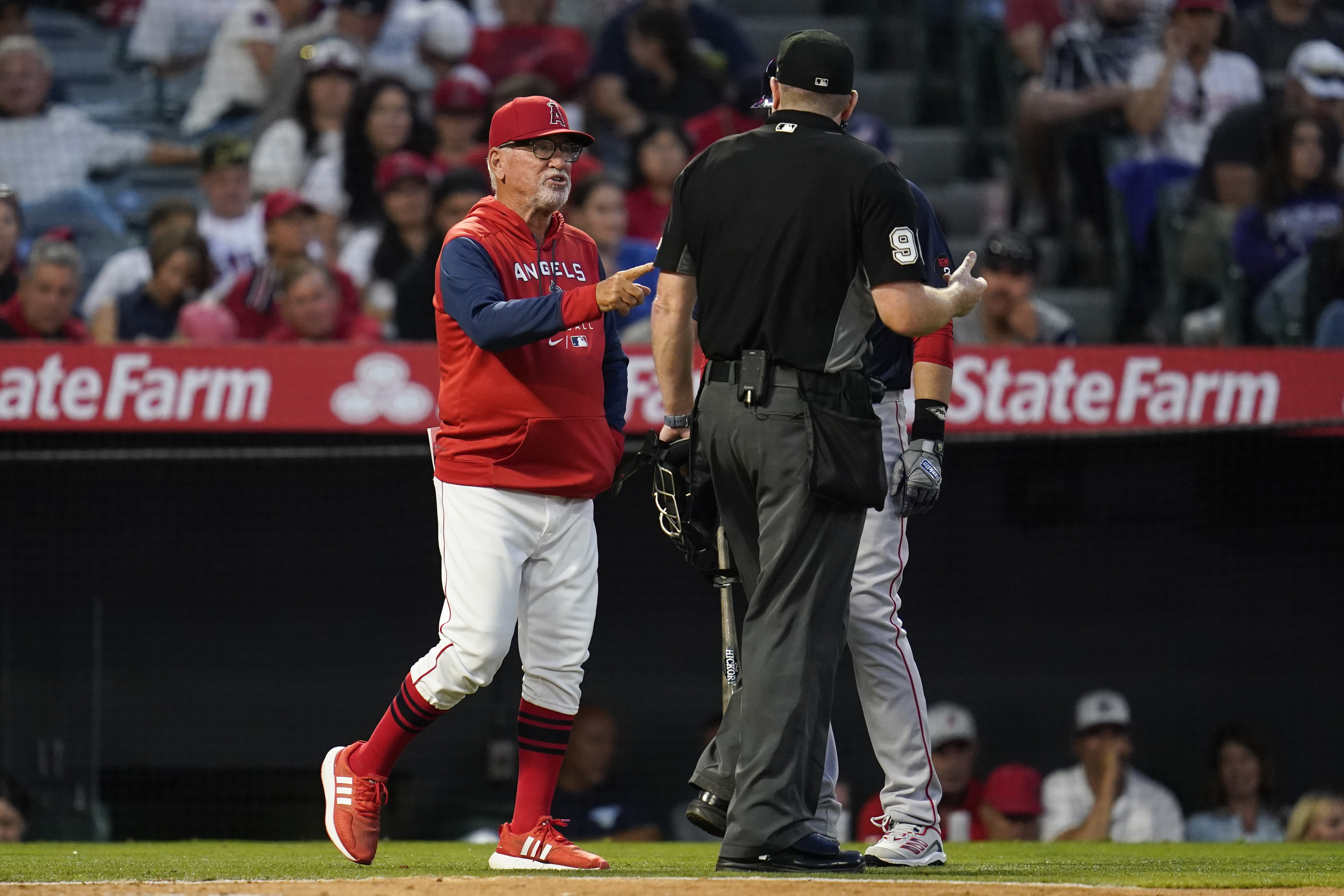 Los Angeles Angels' manager Joe Maddon, left, disputes a stolen base call during the fifth inning of a baseball game against the Boston Red Sox in Anaheim, Calif., Monday, June 6, 2022. 