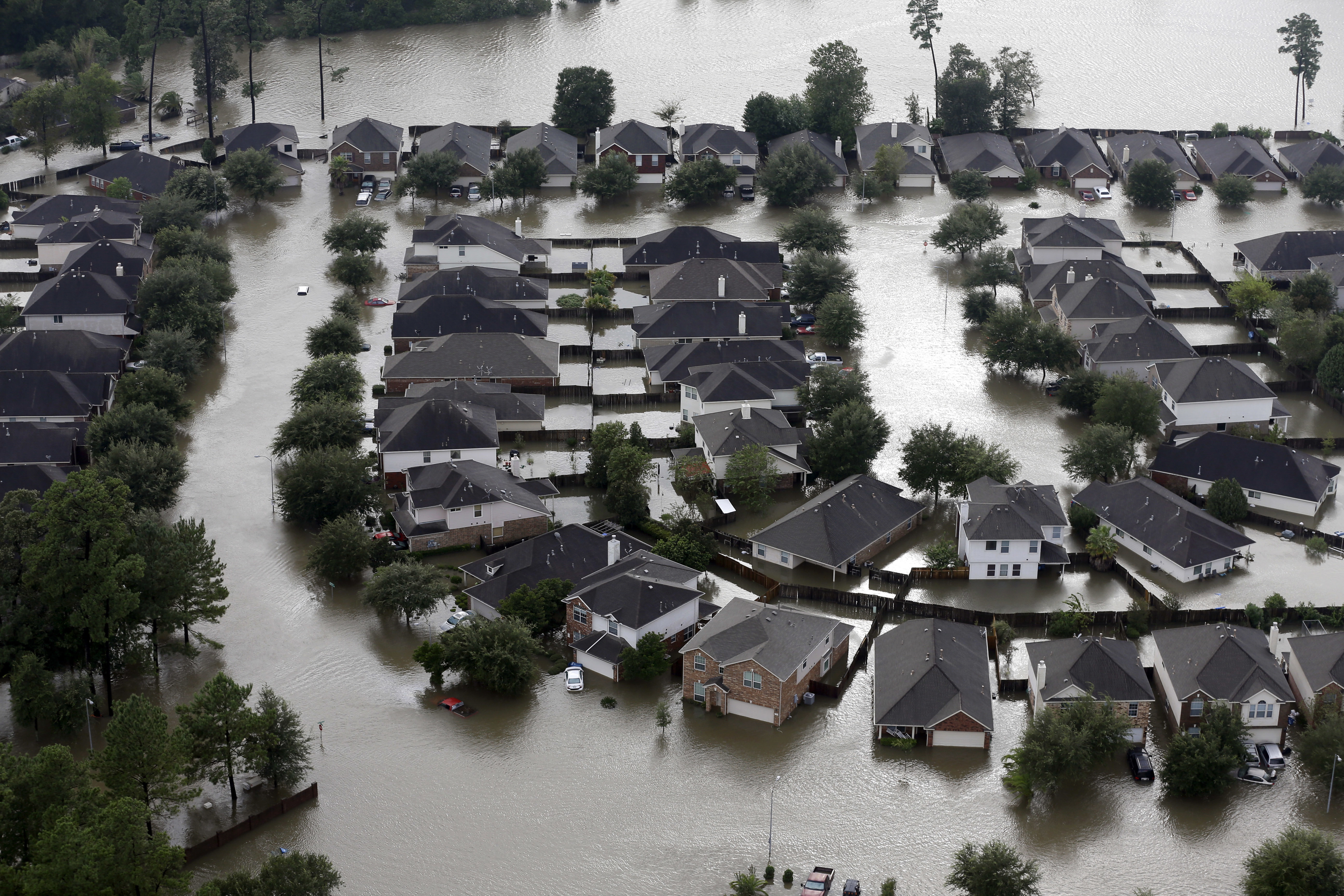 Homes are surrounded by floodwaters from Tropical Storm Harvey in Spring, Texas, Aug. 29, 2017. Experts say more intense storms driven by climate change are boosting contamination risks for privately-owned drinking water wells. 