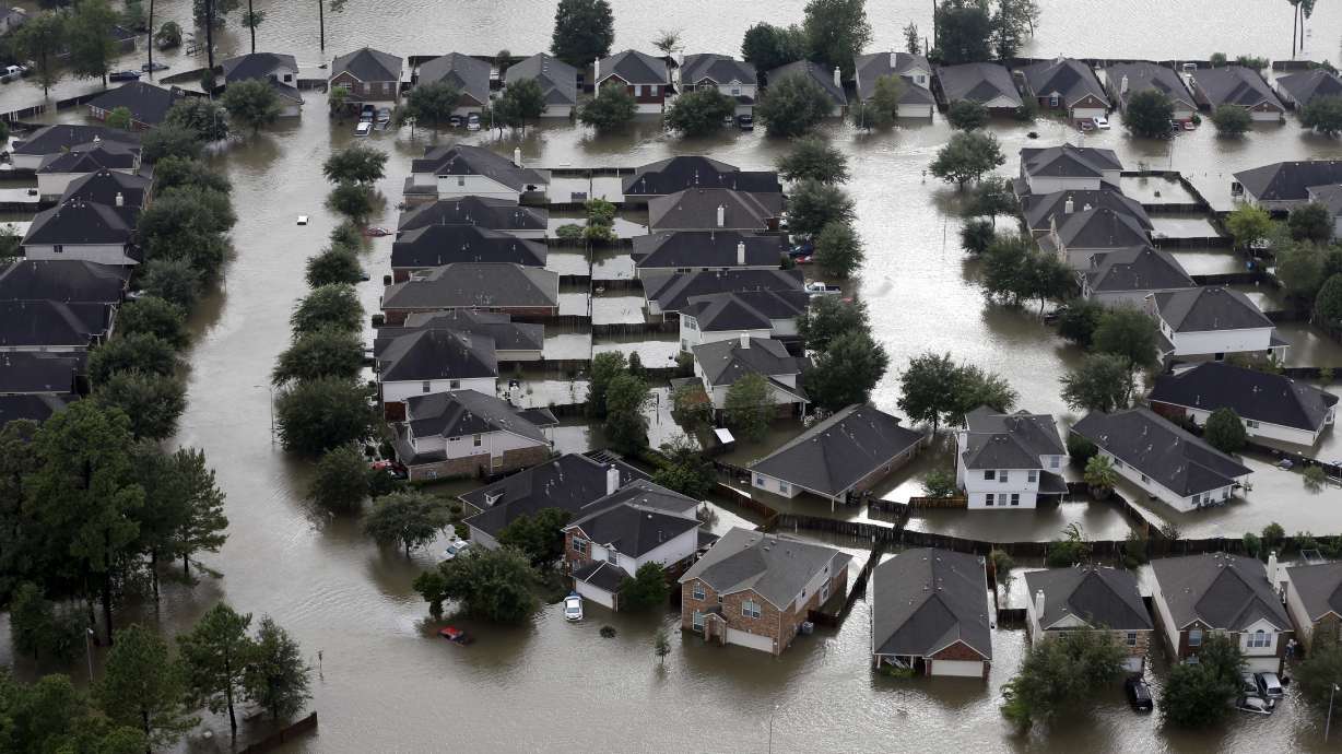 Homes are surrounded by floodwaters from Tropical Storm Harvey in Spring, Texas, Aug. 29, 2017. Experts say more intense storms driven by climate change are boosting contamination risks for privately-owned drinking water wells.