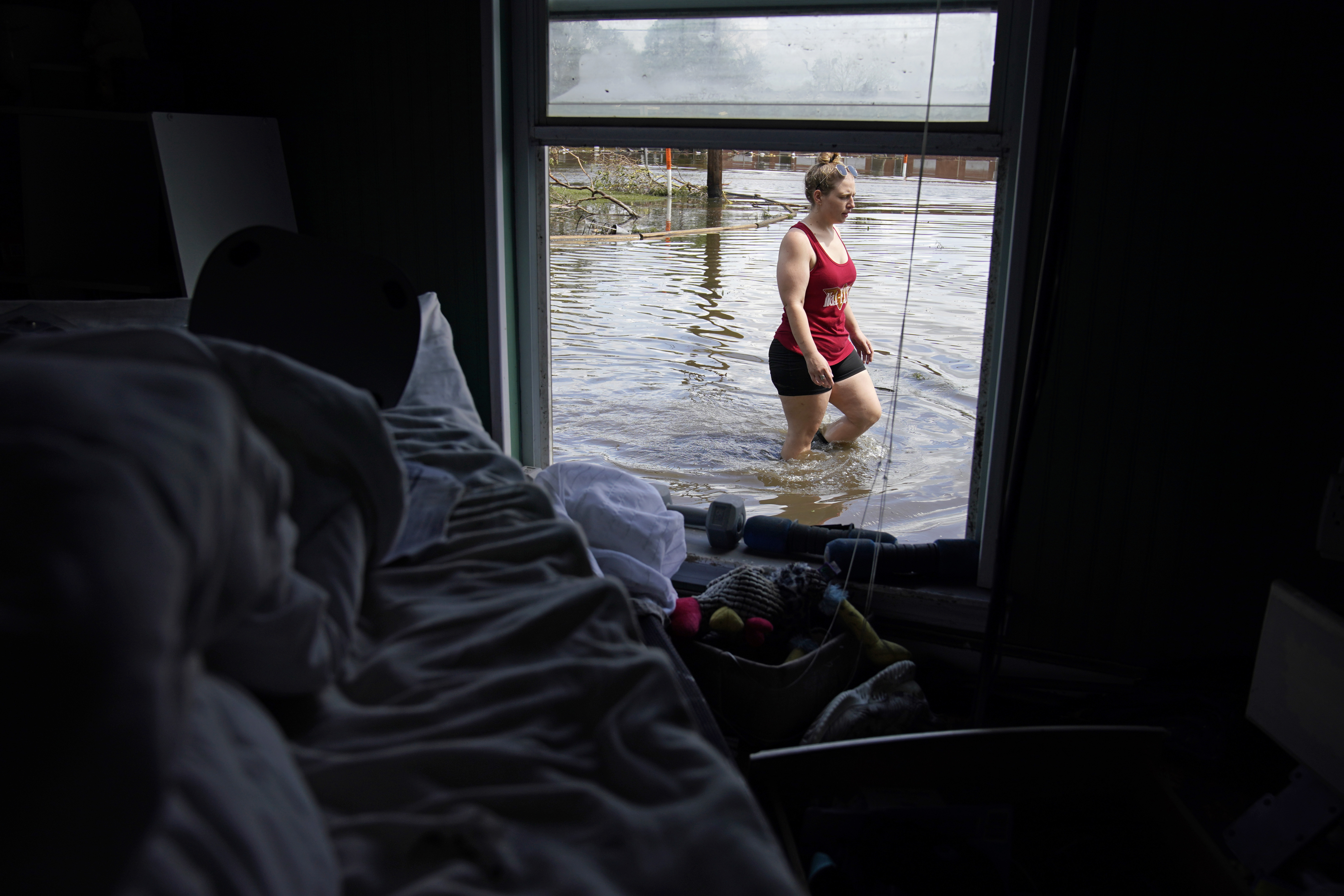 Emily Francois walks through floodwater beside her flood-damaged home in the aftermath of Hurricane Ida on Sept. 1, 2021, in Jean Lafitte, La. Experts say more intense storms driven by climate change are boosting contamination risks for privately-owned drinking water wells.
