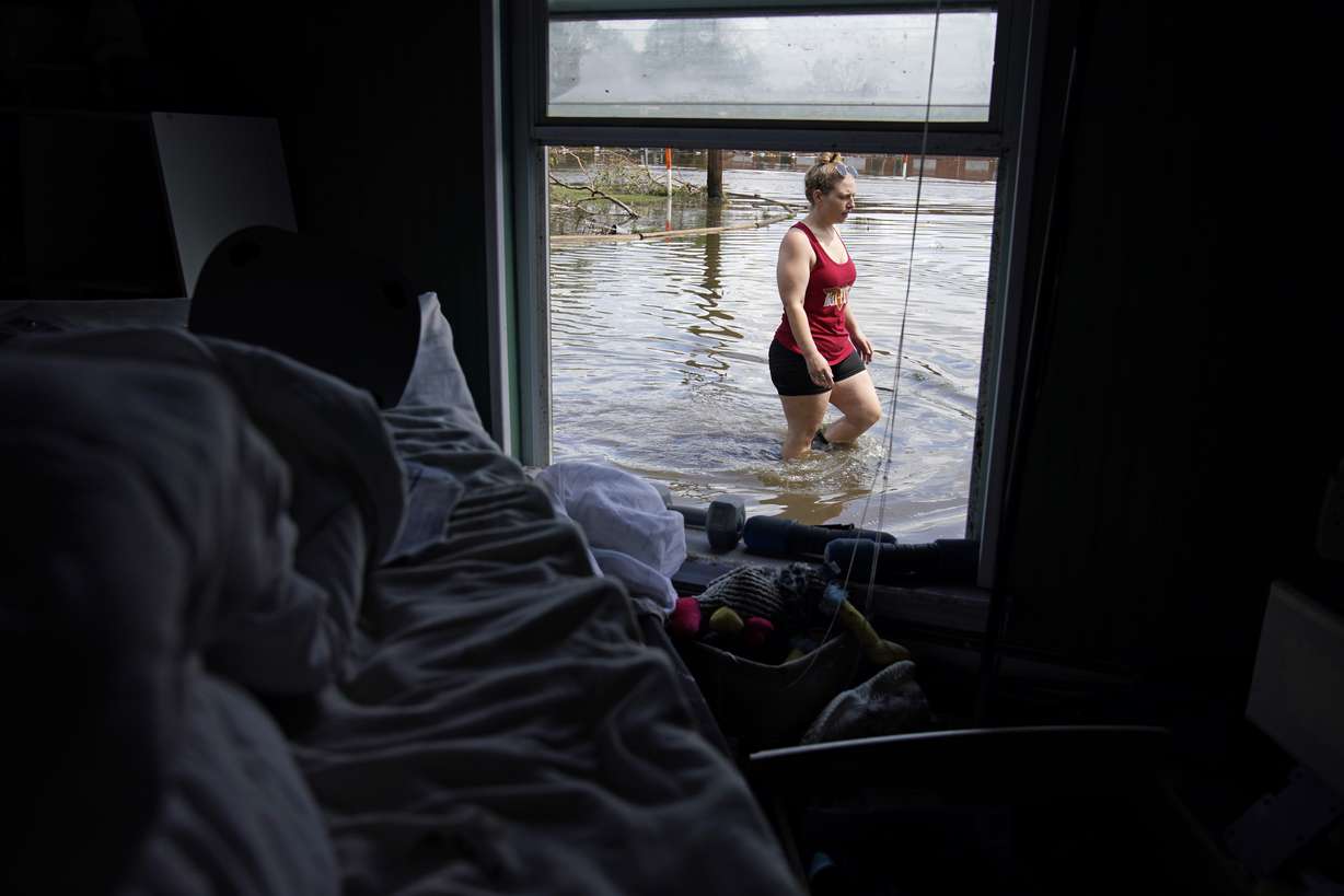 Emily Francois walks through floodwater beside her flood-damaged home in the aftermath of Hurricane Ida on Sept. 1, 2021, in Jean Lafitte, La. Experts say more intense storms driven by climate change are boosting contamination risks for privately-owned drinking water wells.