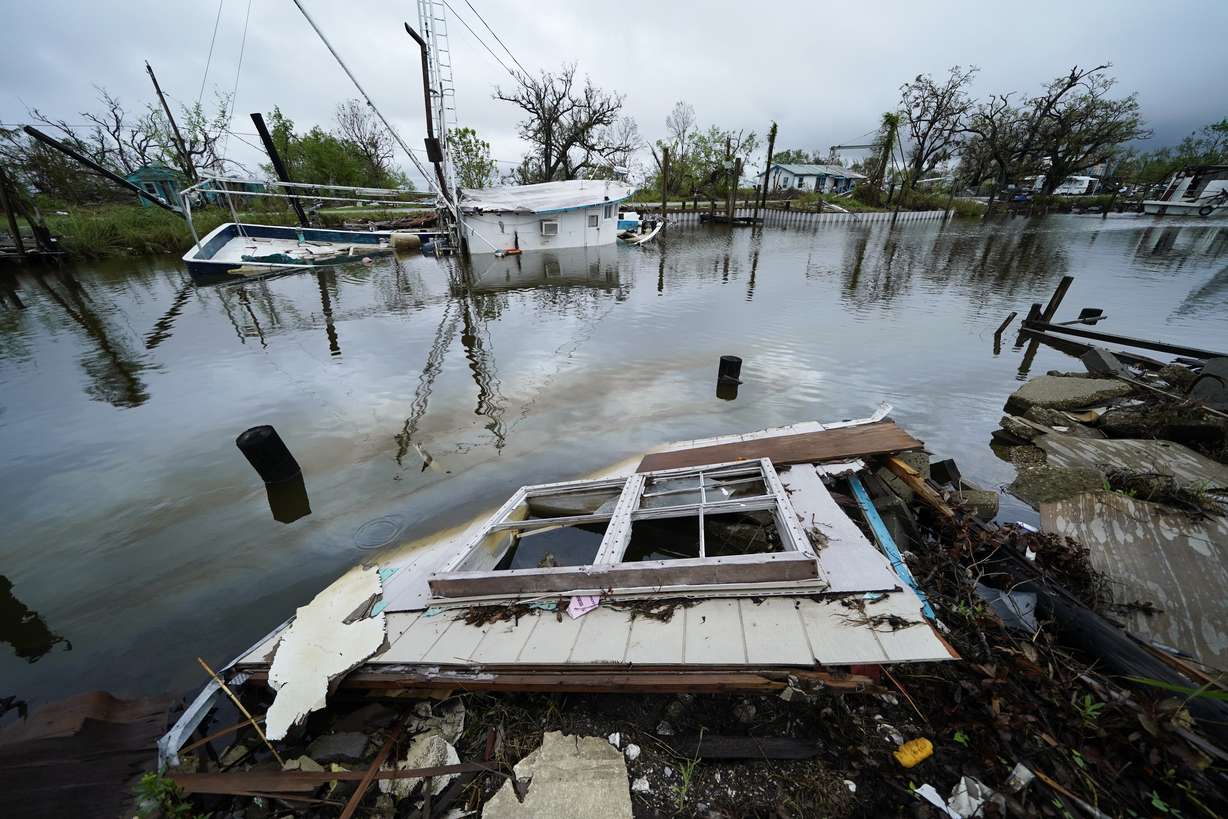 An oil sheen drifts between a sunken shrimp boat and pieces of a destroyed home along Bayou Pointe au Chien in the aftermath of Hurricane Ida in Pointe-aux-Chenes, La., on Sept. 14, 2021. Experts say more intense storms driven by climate change are boosting contamination risks for privately-owned drinking water wells.