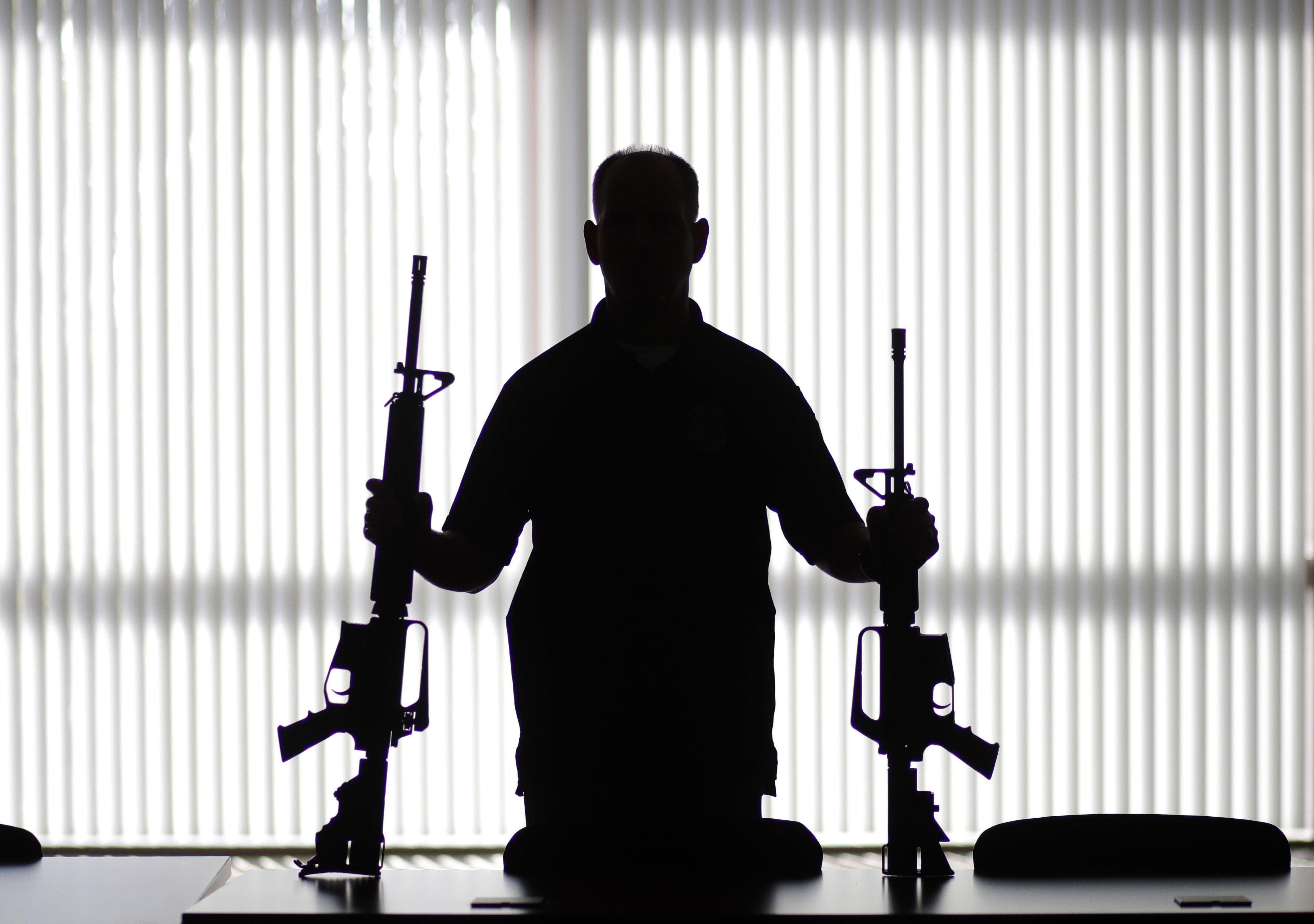 An ATF agent poses with homemade rifles, or “ghost guns,” at an ATF field office in Glendale, Calif., on Aug. 29, 2017. Gun control efforts have routinely stalled in the wake of mass shootings in the United States, with lawmakers unable to agree on the causes of gun violence, and what to do about it.