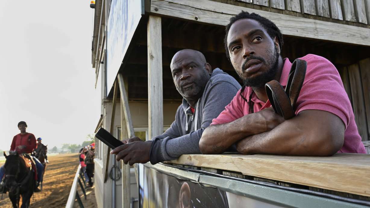 Jerry Dixon Jr., right, trainer of Kentucky Derby winner Rich Strike, watches the horse as his father, Jerry Dixon Sr., times the workout around Churchill Downs in Louisville, Ky., May 29, 2022. Dixon Jr., a fourth-generation horseman who works with his father, is one of a handful of Black horsemen who can be seen around the backside barns of tracks working as trainers, grooms and hot walkers, but their numbers are scarce compared to the overwhelming presence of Latino workers.