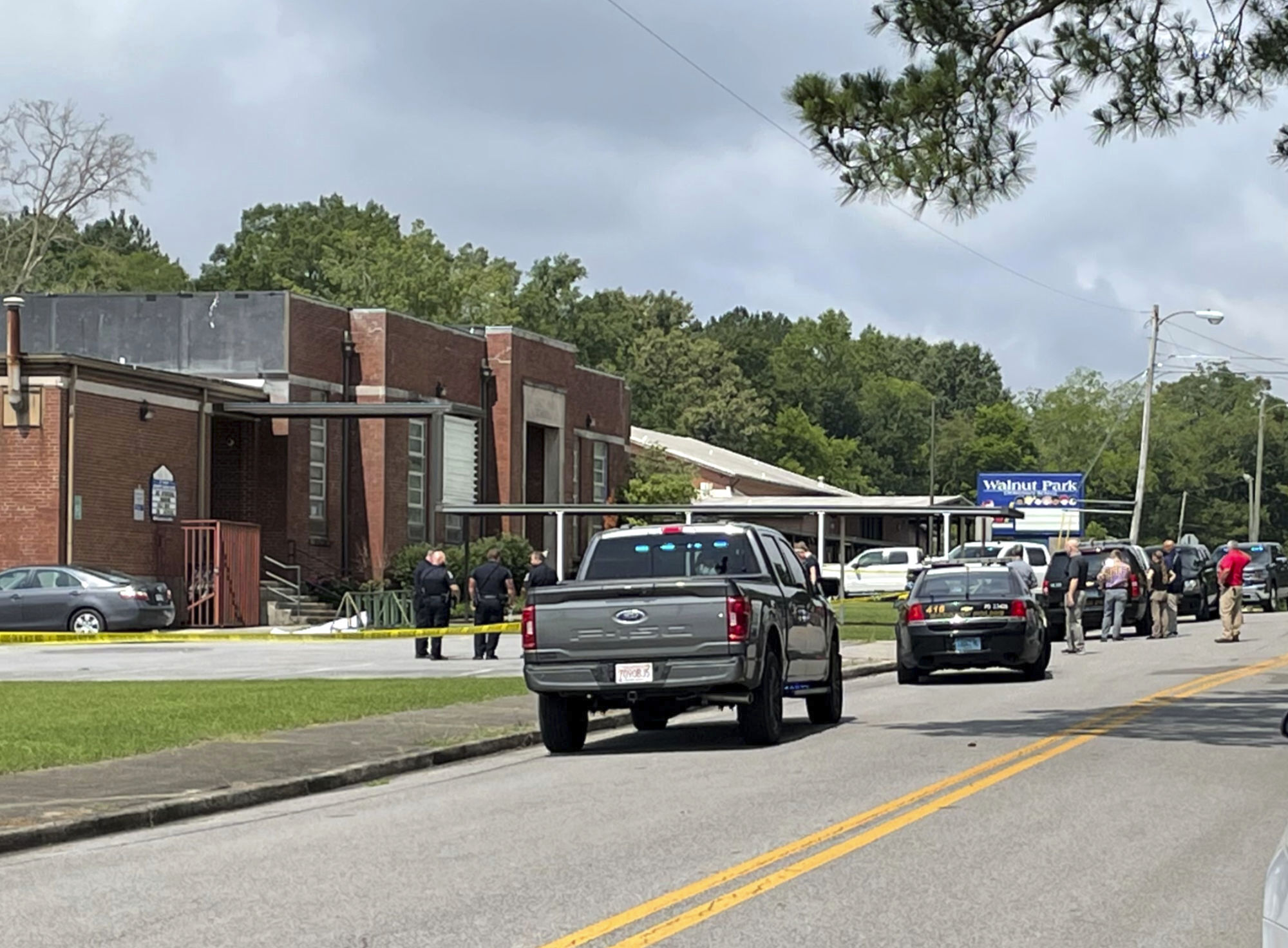 Officials gather outside Walnut Park Elementary School where a man was shot to death by police, Thursday, in Gadsden, Ala.
