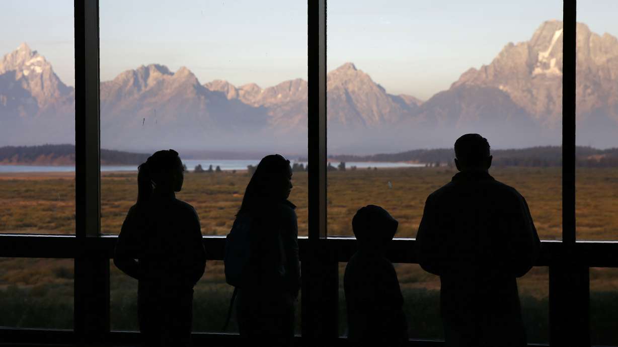 Visitors watch the morning sun illuminate the Grand Tetons from within the Great Room at the Jackson Lake Lodge in Grand Teton National Park in Wyoming on Aug. 28, 2016. Heather Mycoskie, 40, accused of intentionally providing wrong information in the search for a missing man in Grand Teton National Park has been banned from the park and ordered to pay restitution.