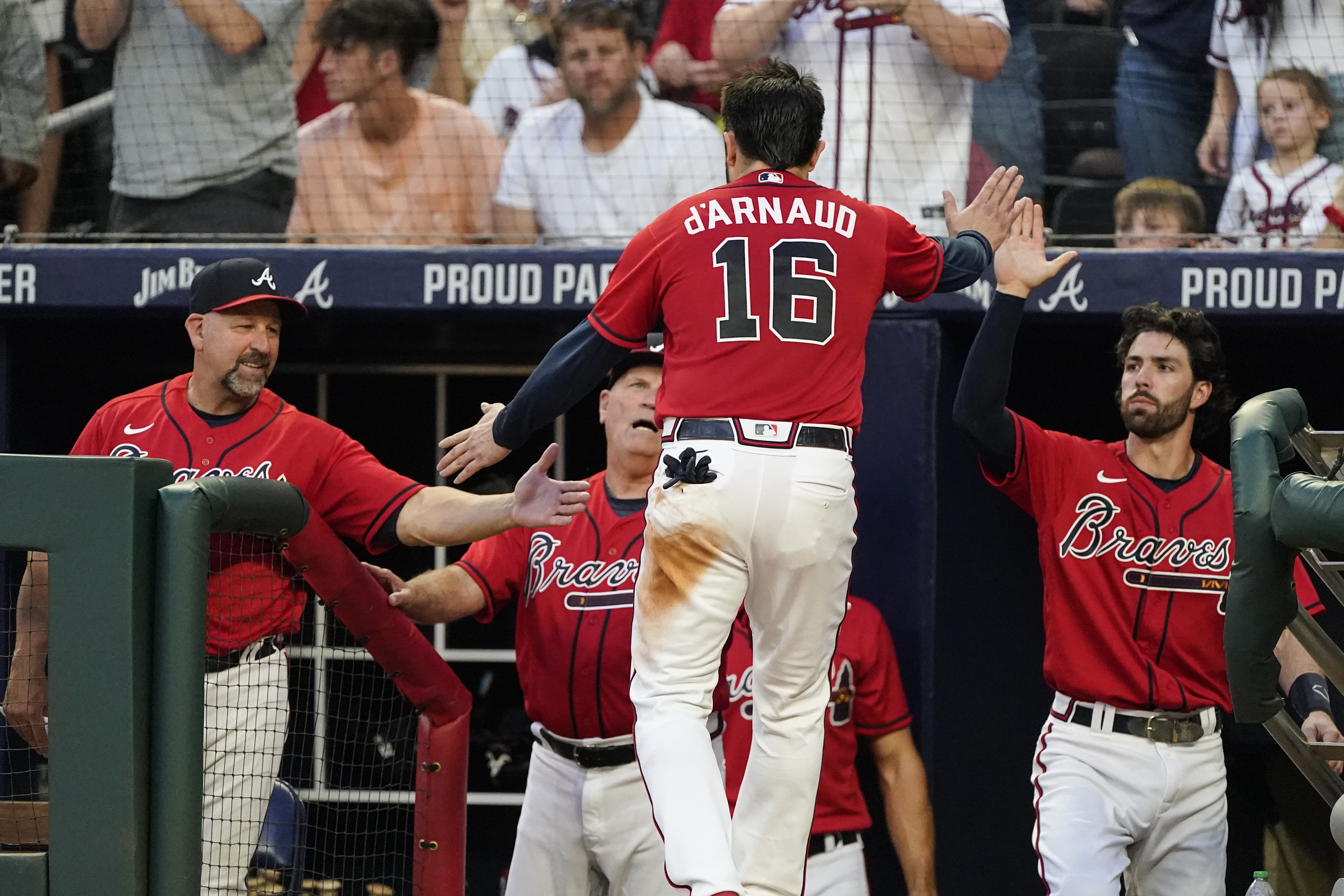 Atlanta Braves' Travis d'Arnaud (16) is greeted at the dugout by bench coach Walt Weiss, left, manager Brian Snitker, center, and Dansby Swanson, right, after scoring on an Ozzie Albies double during the fourth inning of a baseball game against the Pittsburgh Pirates on Friday, June 10, 2022, in Atlanta. 