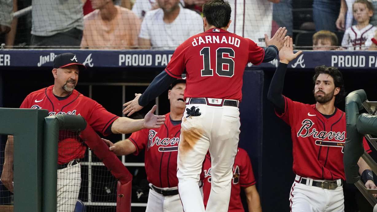 Atlanta Braves' Travis d'Arnaud (16) is greeted at the dugout by bench coach Walt Weiss, left, manager Brian Snitker, center, and Dansby Swanson, right, after scoring on an Ozzie Albies double during the fourth inning of a baseball game against the Pittsburgh Pirates on Friday, June 10, 2022, in Atlanta.