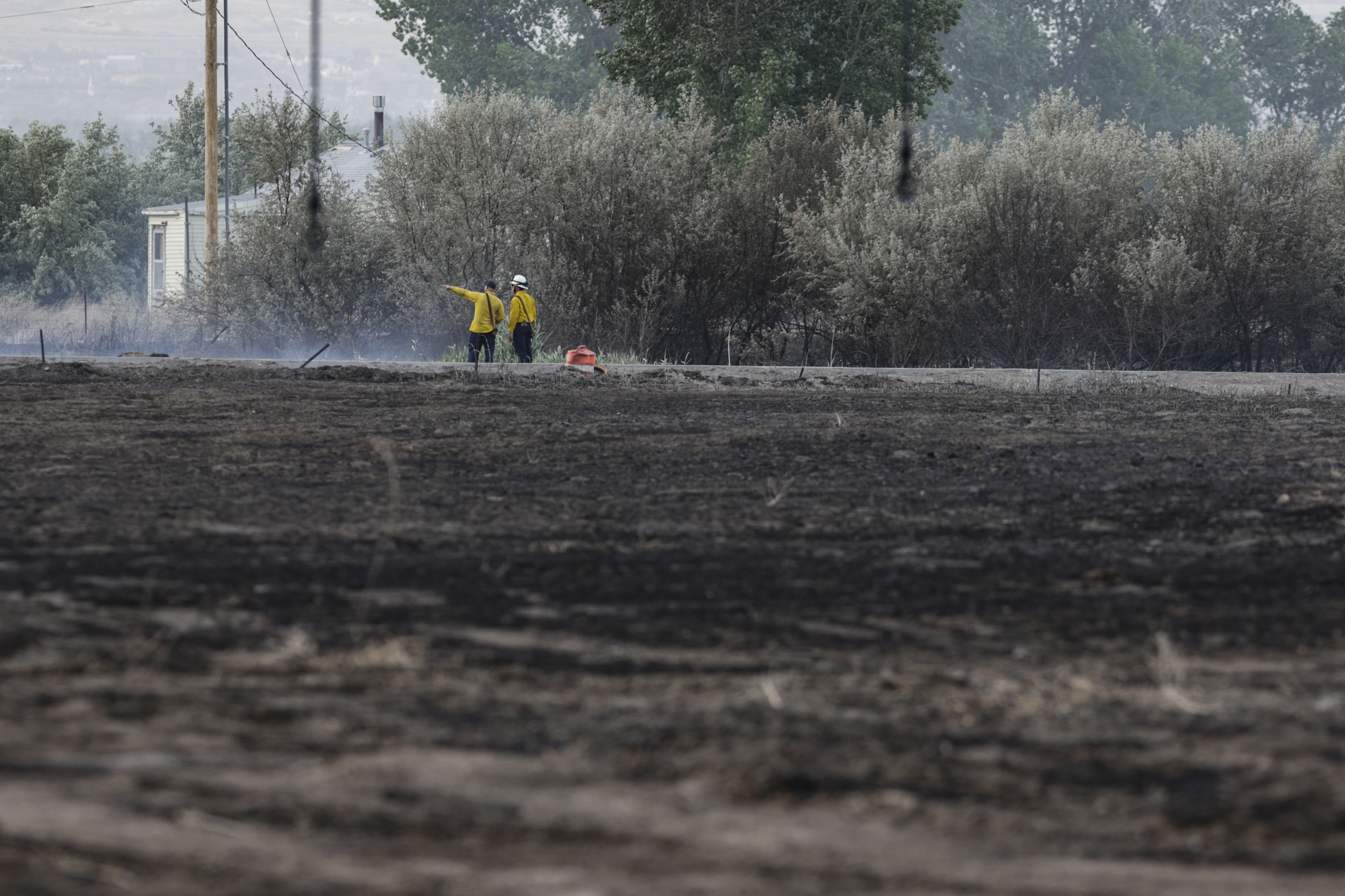 Saratoga Springs firefighters work at the scene of a vegetation fire in Saratoga Springs on Sunday. Record-breaking heat, small fires and wind advisories hit Utah Sunday before a cold front moved in that is set to bring relief through the night and into Monday.