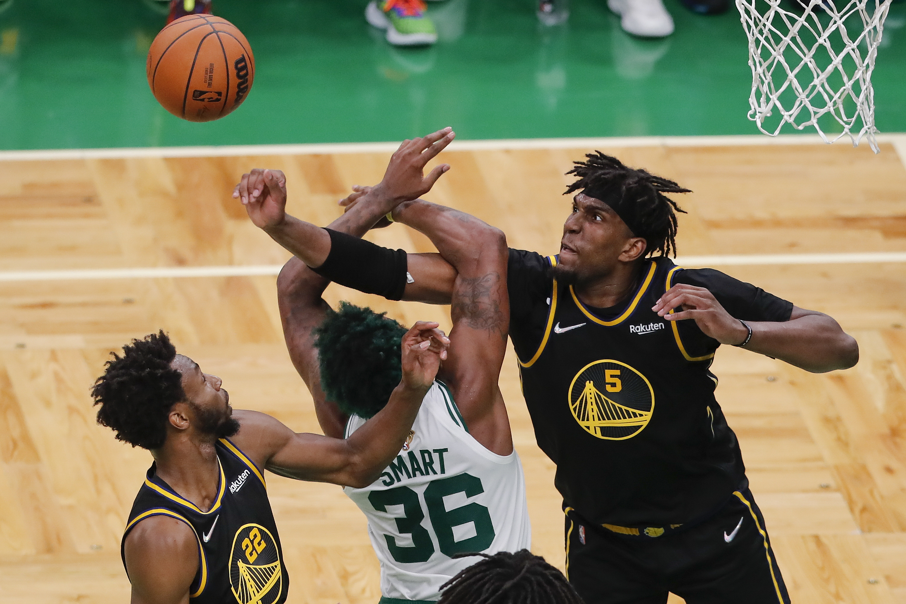 Golden State Warriors center Kevon Looney (5) and forward Andrew Wiggins (22) battle for a rebound against Boston Celtics guard Marcus Smart (36) during the fourth quarter of Game 4 of basketball's NBA Finals, Friday, June 10, 2022, in Boston. 