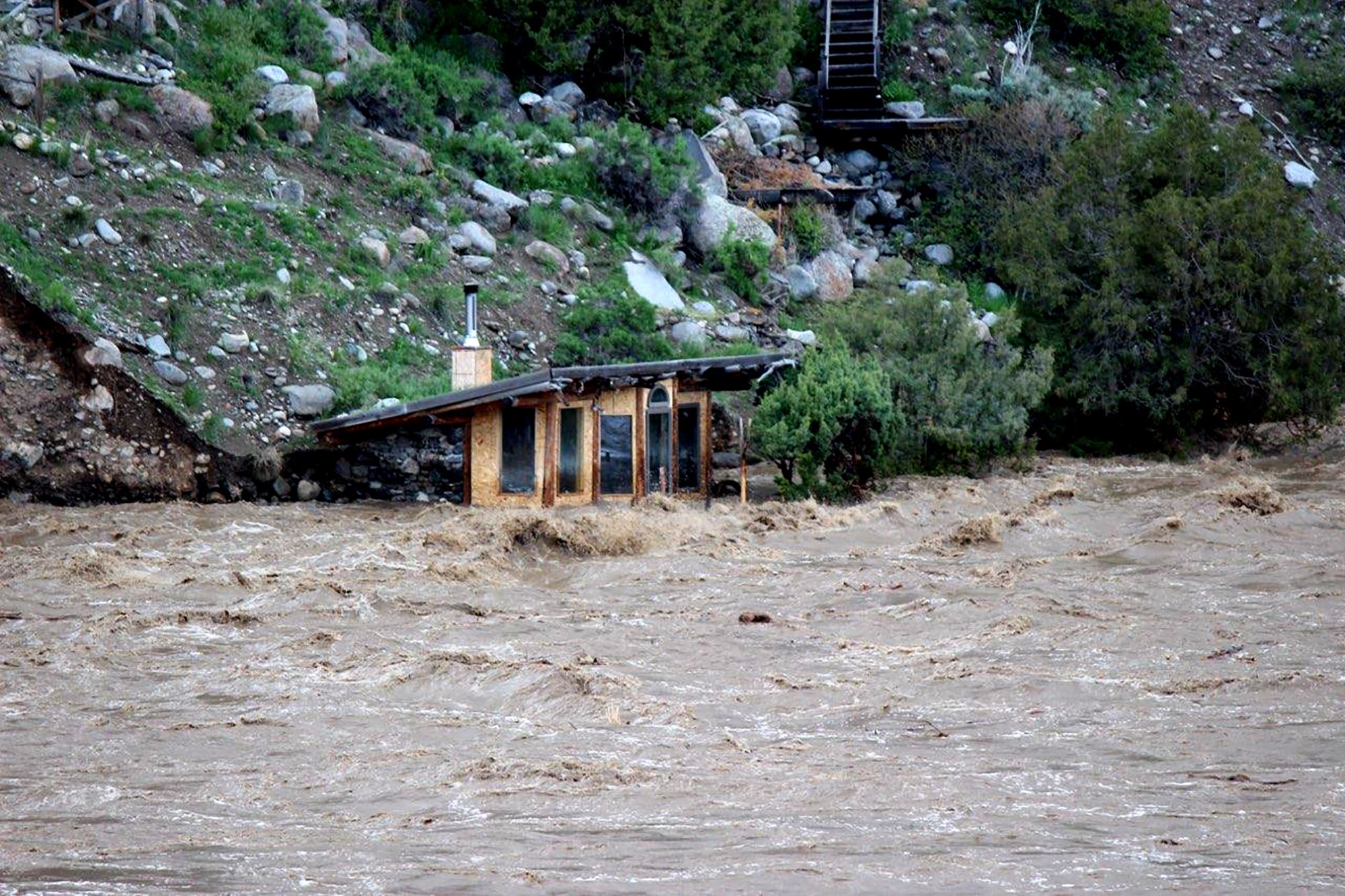 In this photo provided by Sam Glotzbach, the fast-rushing Yellowstone River flooded what appeared to be a small boathouse in Gardiner, Mont., on Monday, just north of Yellowstone National Park.