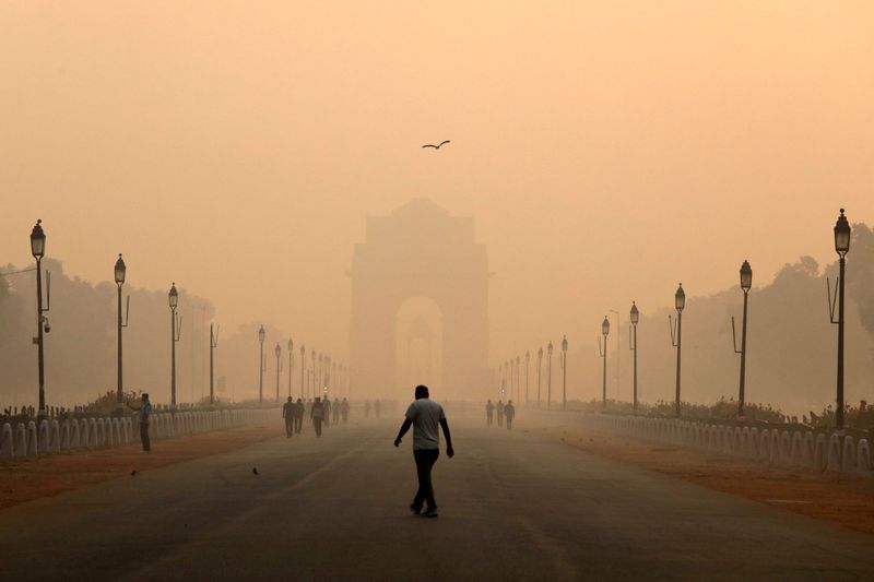 A man walks in front of the India Gate shrouded in smog in New Delhi, India, on Oct. 29, 2018. Chronic air pollution cuts average global life expectancy by more than two years per person, a study published on Tuesday showed, an impact comparable to that of smoking and far worse than HIV/AIDS or terrorism.