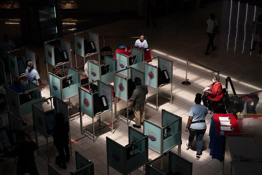 Election workers help as people vote at a polling place Tuesday, in Las Vegas. 