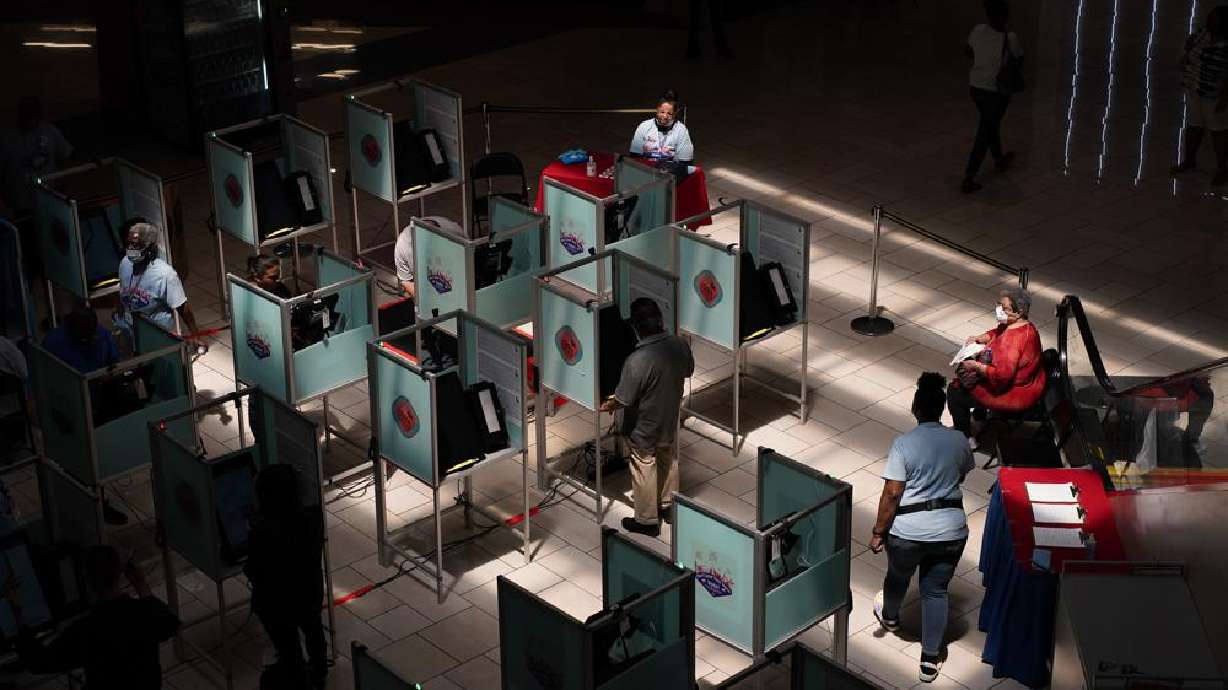 Election workers help as people vote at a polling place Tuesday, in Las Vegas.