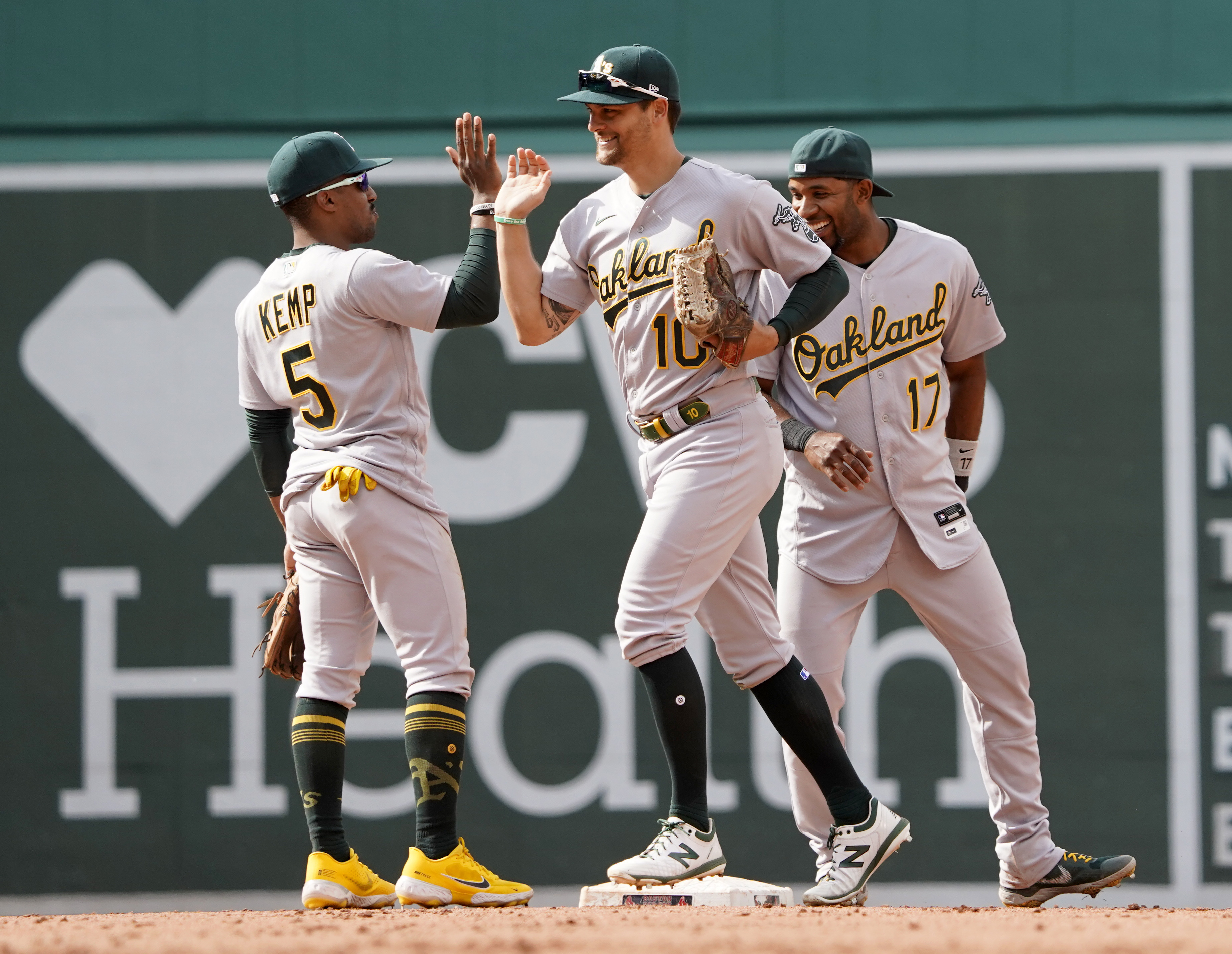 Oakland Athletics players, from left, Tony Kemp (5), Chad Pinder, and Elvis Andrus (17) celebrate after defeating the Boston Red Sox in a baseball game at Fenway Park, Thursday, June 16, 2022, in Boston. 