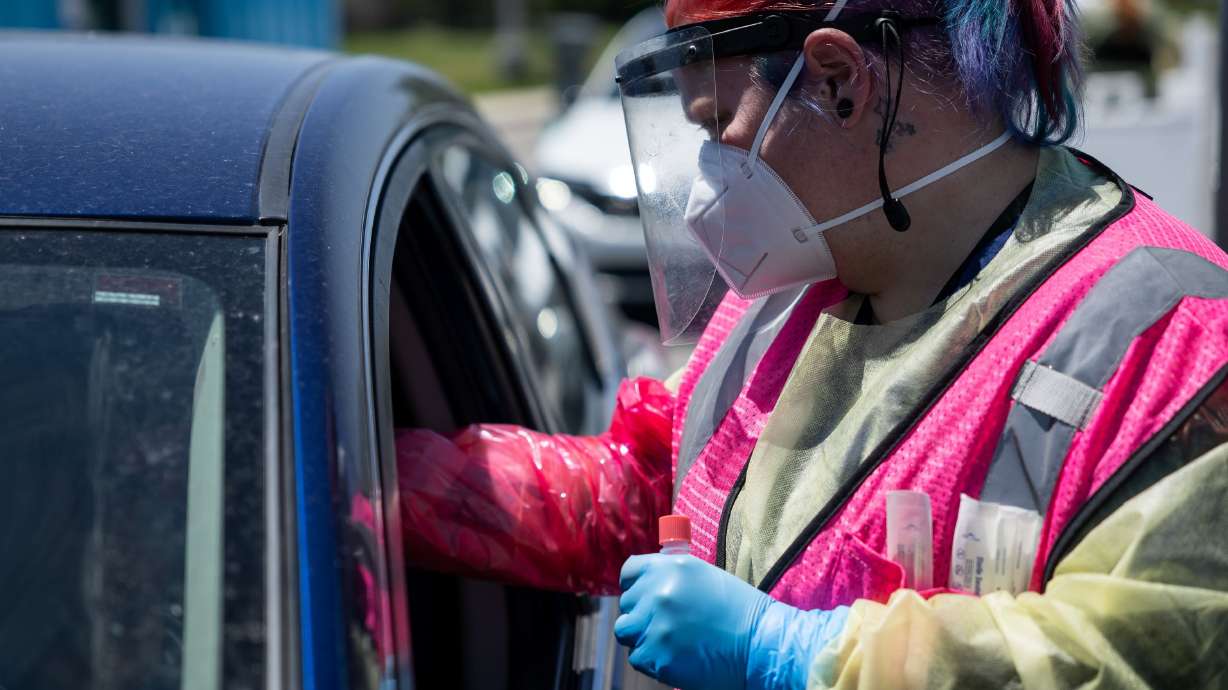 Megan Clay administers a COVID-19 test at a NOMI Health drive-thru test site in West Valley City on June 10. Five of Utah's 29 counties are now at a high community level of COVID-19 where everyone should be wearing masks indoors and avoiding nonessential activities if they're at high risk, according to the CDC.