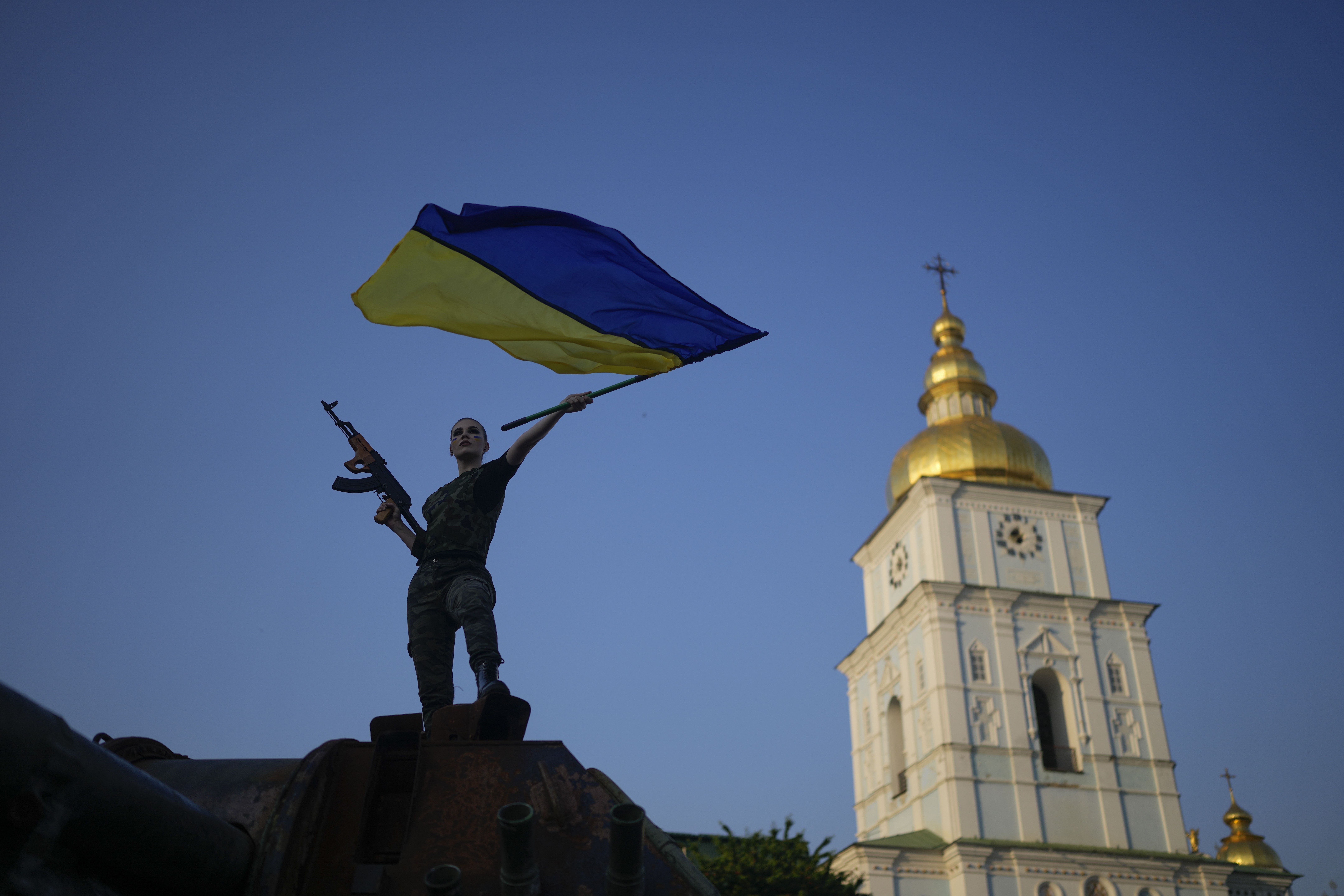 A woman brandishes a Ukrainian flag standing on top of a destroyed Russian tank in Kyiv, Ukraine, June 10, 2022. The European Commission recommended that Ukraine and Moldova be granted status as candidates to join the European Union on Friday, the first official step in the process of joining the bloc of nations.