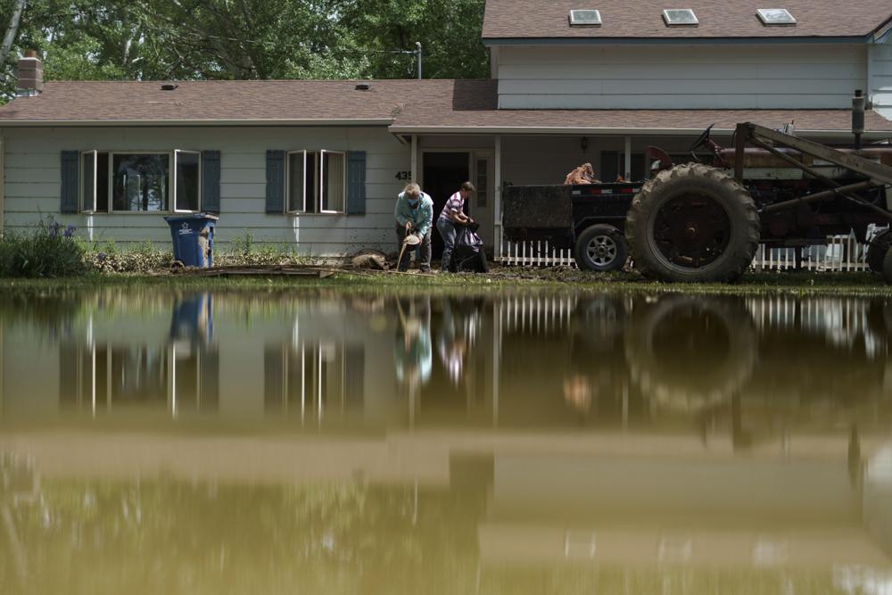 Aileen Rogers, right, and Melody Murter help clean out a friend's house badly damaged by the severe flooding in Fromberg, Mont., Friday. Montana Governor Greg Gianforte is back in Montana and under fire for not hurrying home from a vacation more quickly and for keeping the public in the dark as to his whereabouts.