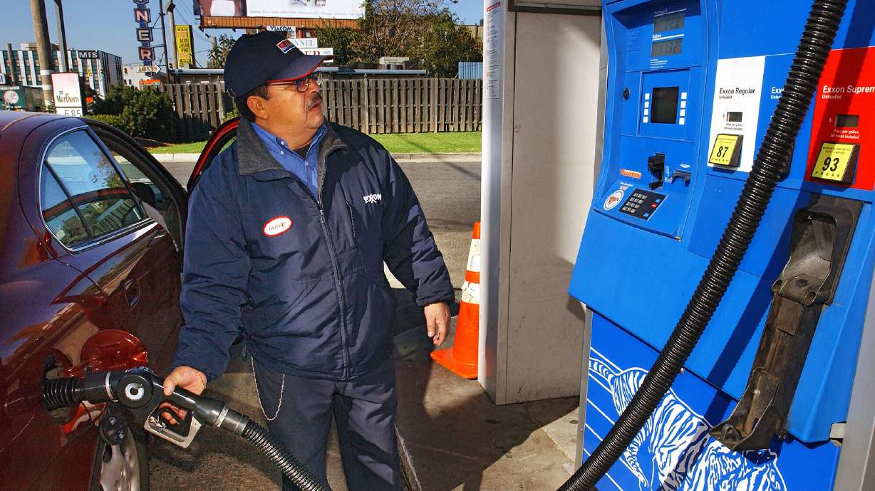 Station attendant George Samaniego pumps gas at an Exxon gas station in Jersey City, New Jersey, Oct. 28, 2004. People in New Jersey and Oregon are not allowed to touch the gas nozzle. Changing that law is not so simple in those states.