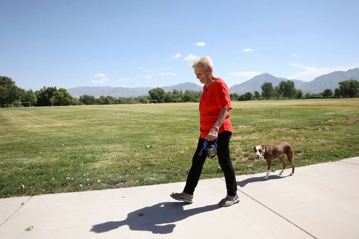 A woman walks her dog around the Salt Lake County Rugby Fields in Murray on Friday. Salt Lake County is planning to replace some park strips and athletic fields with water-wise landscaping and artificial turf.