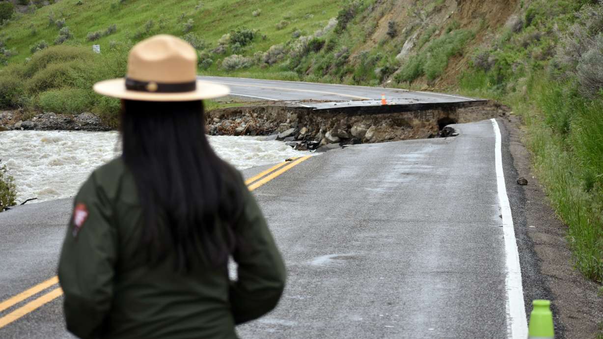A Yellowstone National Park ranger is seen standing near a road wiped out by flooding along the Gardner River the week before, near Gardiner, Mont., Sunday. Park officials said they hope to open most of the park within two weeks.