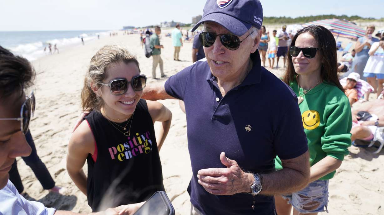 President Joe Biden talks to the media after walking on the beach with his granddaughter Natalie Biden, left, and his daughter Ashley Biden, right, Monday at Rehoboth Beach, Del. He says he's considering a federal holiday on the gasoline tax.