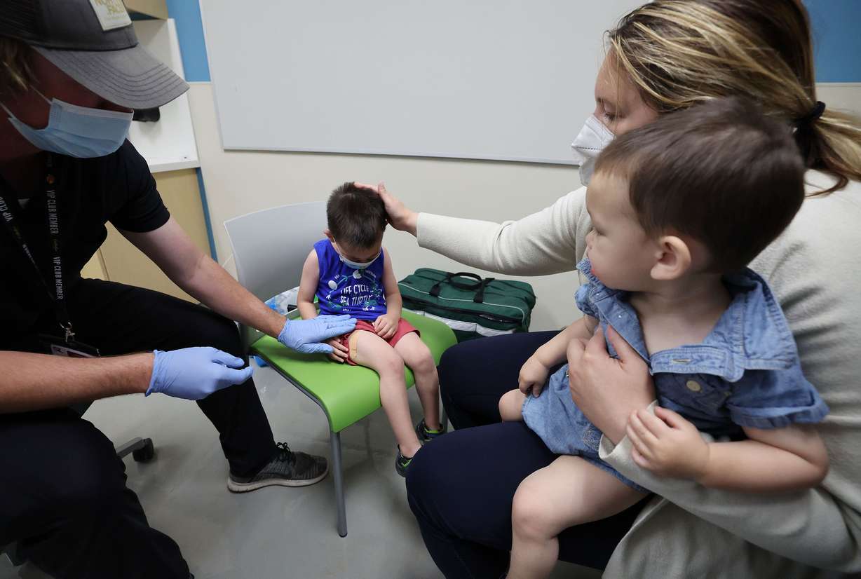 Registered nurse Wyatt Hanvey, left, and Melanie Mallory, right, who is holding son Tai Luong, 1, comfort Mallory’s other son, James Luong, 3, after he received his COVID-19 vaccine at the Salt Lake Public Health Center in Salt Lake City on Tuesday.