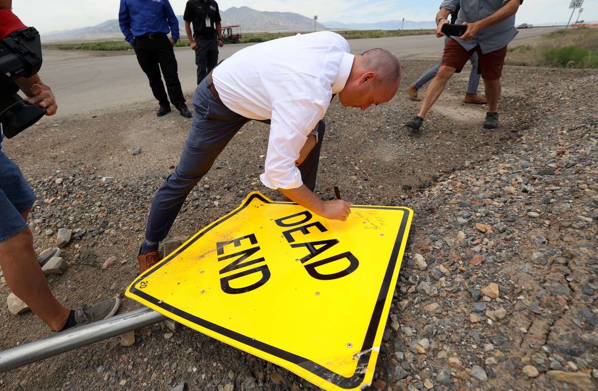 Gov. Spencer Cox signs a “dead end” sign “To new beginnings” after taking it down, at the suggestion of House Speaker Brad Wilson, R-Kaysville, on the road to the new Utah State Correctional Facility in Salt Lake City on Wednesday. A ribbon-cutting ceremony for the facility was held Wednesday.