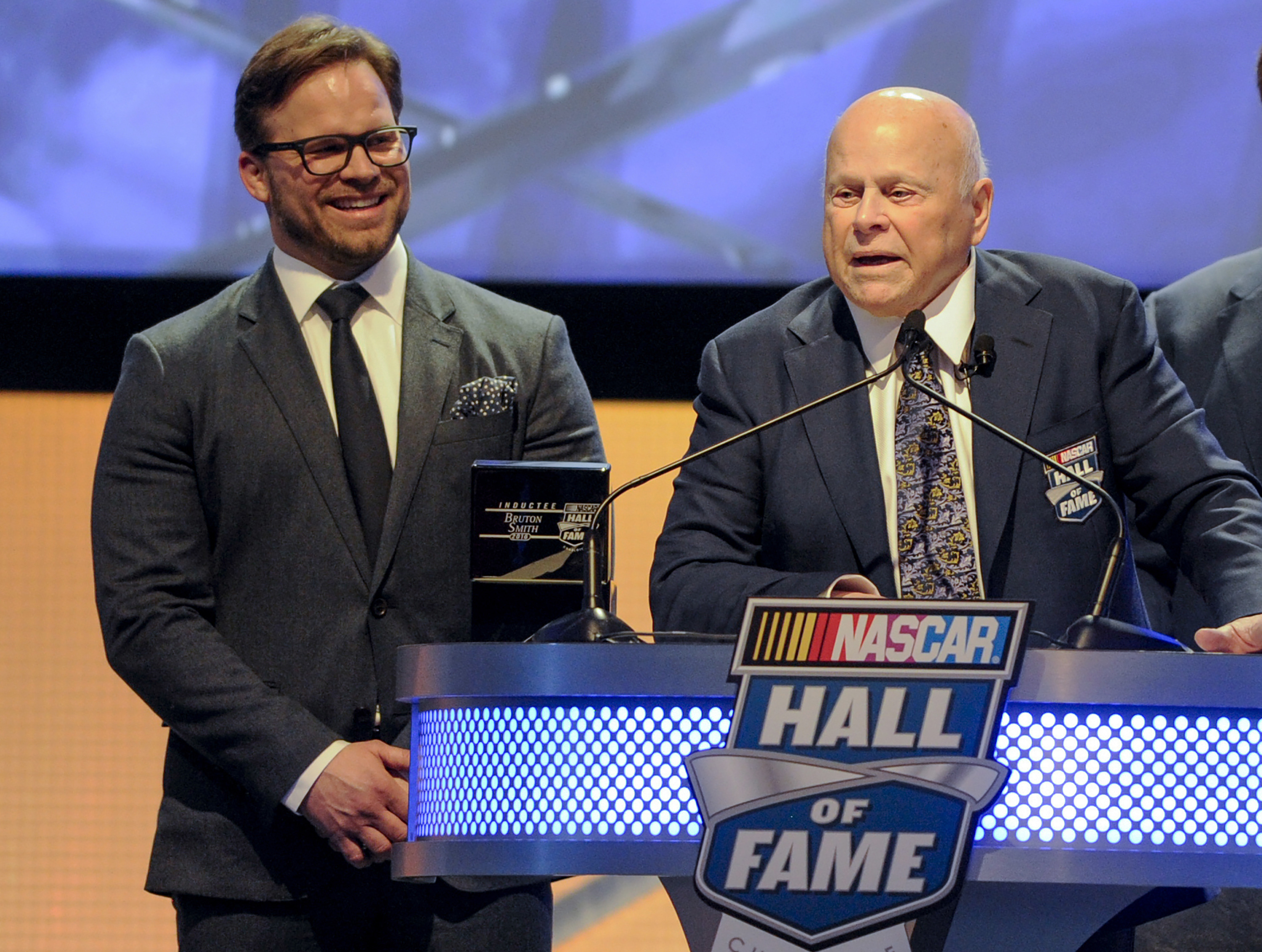 FILE - Hall of Fame inductee Bruton Smith entertains the crowd as his son, Marcus Smith, left, looks on during NASCAR Hall of Fame Induction ceremonies in Charlotte, N.C., Saturday, Jan. 23, 2016.  Bruton Smith, a North Carolina native and entrepreneur who fell in love with auto racing and parlayed it into a career as an eccentric and successful promoter, died Wednesday, June 22, 2022 of natural causes. He was 95. His death was confirmed by Speedway Motorsports, the company he founded and owns and operates 11 race tracks across the United States. 