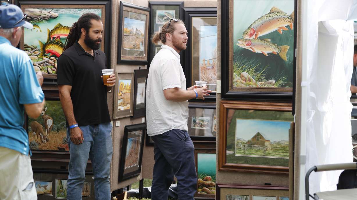 Utah Arts Festival attendees look at paintings during the 2021 event. The annual Utah Arts Festival will return to Liberty Square in full force, Thursday through Sunday, with several new additions to the usual festivities.