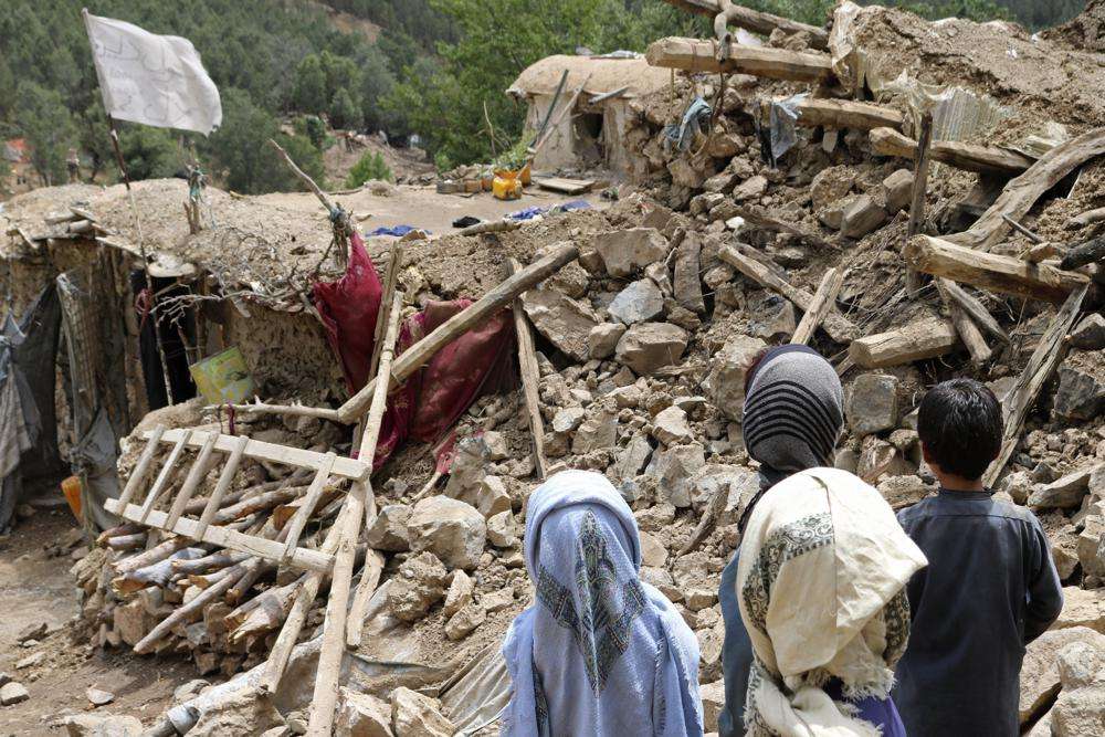 Afghan children stand near a house that was destroyed in an earthquake in the Spera District of the southwestern part of Khost Province, Afghanistan, Wednesday. A powerful earthquake struck a rugged, mountainous region of eastern Afghanistan early Wednesday, killing at least 1,000 people and injuring 1,500 more in one of the country's deadliest quakes in decades, the state-run news agency reported.