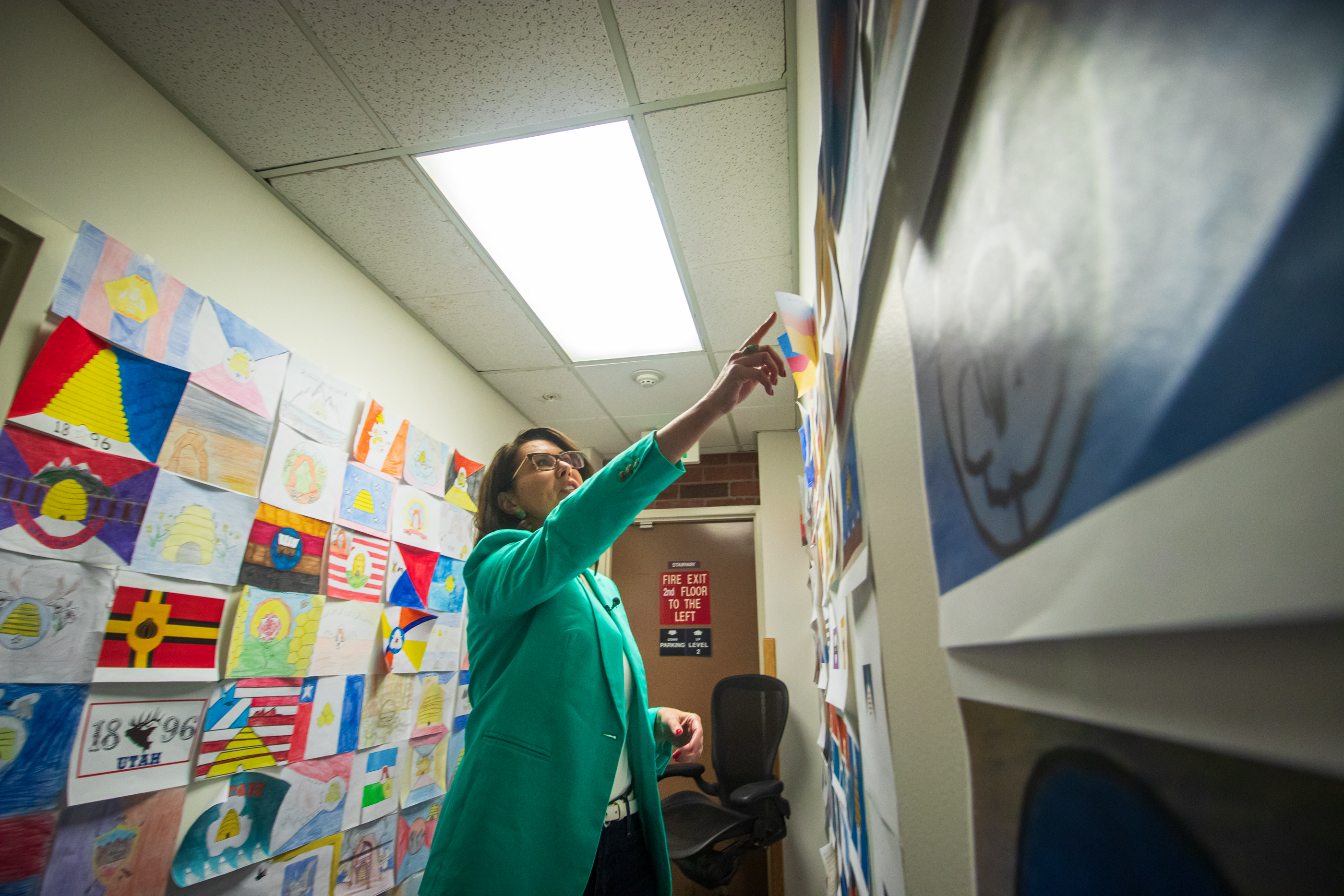 Lt. Gov. Deidre Henderson points to one of the 5,703 Utah state flag designs posted to the walls of the Utah office building in Millcreek on Thursday. The state will narrow the field down to about 20 by August as it searches for a new state flag.